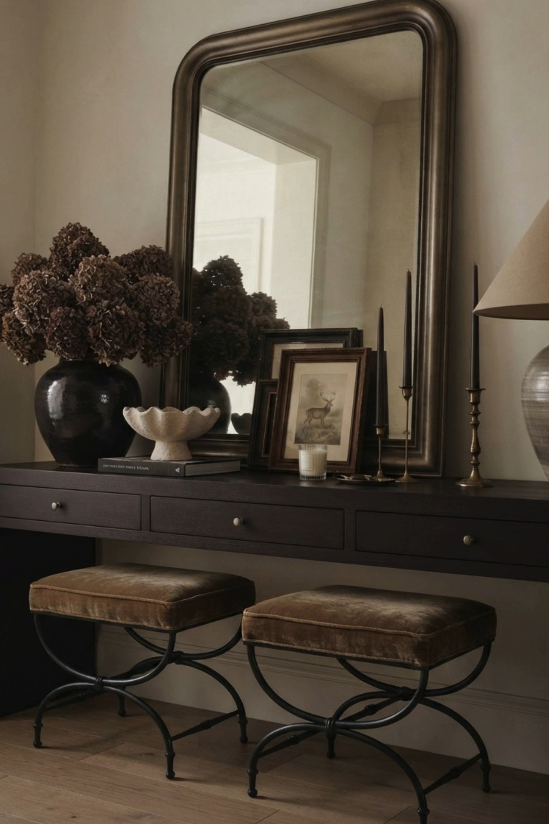 Moody Entryway Console Styling 🤎 This collected entryway blends organic modern decor with old-world traditional style, featuring a dark wood console table, oversized vintage-inspired mirror, velvet stools, antique brass candlesticks, framed artwork, and earthy ceramic accents. A dramatic black vase filled with dried hydrangeas adds rich texture and seasonal warmth, while layered art, sculptural decor, and soft neutral tones create an elevated designer look perfect for an entryway, foyer, or hallway. 🖤 If you want to see more content like this, FOLLOW maeveandmodern on LTK, Instagram, and Pinterest! Check out our blog where we post daily, maeveandmodern.com! Entryway Console Styling | Entryway Decor Ideas | Foyer Decor | Console Table Decor | Dark Wood Console Table | Oversized Mirror | Vintage Inspired Mirror | Moody Home Decor | Organic Modern Decor | Traditional Home Decor | Old World Interiors | Collected Home Decor | Dried Hydrangeas | Fall Floral Arrangement | Black Ceramic Vase | Velvet Stools | Accent Stools | Antique Brass Candlesticks | Taper Candle Holders | Vintage Framed Art | Layered Artwork | Ceramic Table Lamp | Neutral Home Decor | Earth Tone Decor | Transitional Interiors | Designer Entryway | Hallway Decor Ideas | Fall Entryway Decor | Cozy Home Inspiration | Timeless Interior Design

#LTKHome #LTKSaleAlert #LTKSeasonal