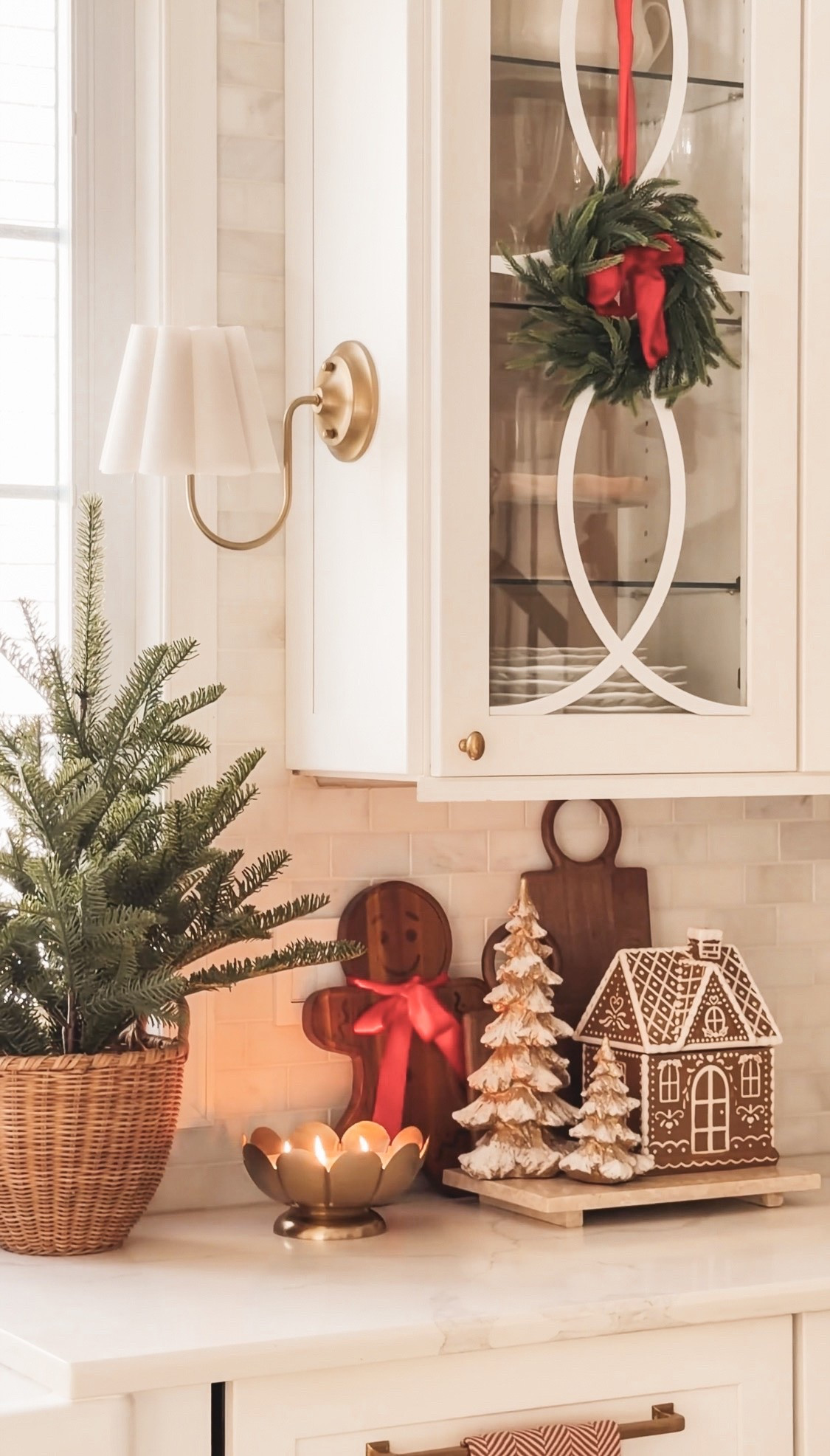 Cozy Christmas corner with gingerbread house and gingerbread cutting board, mini Christmas tree and mini wreaths haunting in the cabinets