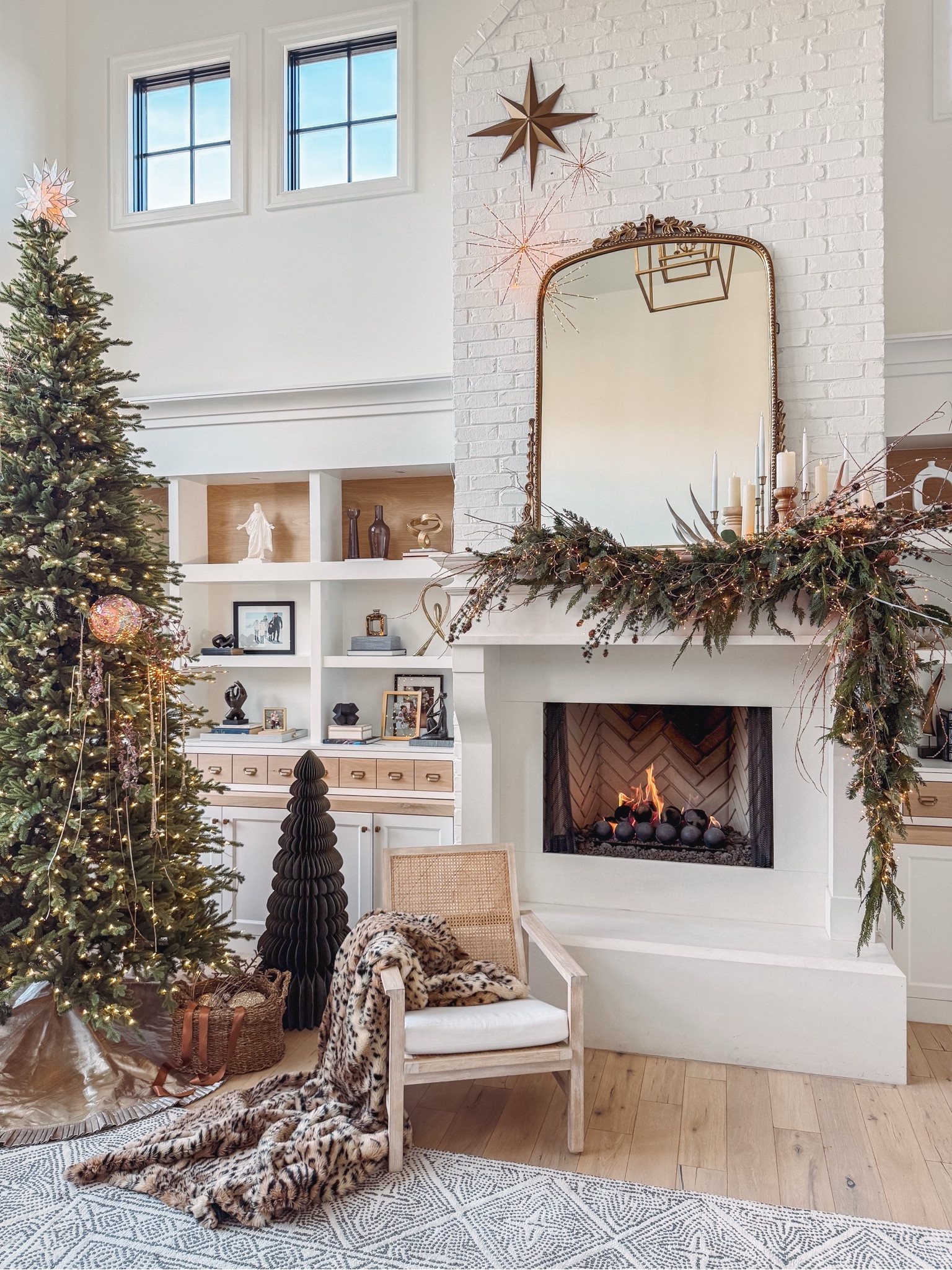 My Christmas mantel is finished! 
I’ve used two types of 9ft garland (1 multi & 1 faux cedar).
Special Copper Twinkle lights, flameless candles, Christmas tree decorations, twinkle stars, glowing orbs, and a large paper tree! My Christmas tree is 12ft tall with light pole technology. Also comes in 6ft- 10ft options!

My mantel is 7ft tall & 5ft wide for reference. My gold mirror is 5ft tall- comes in 3ft & 7ft option too. 

My batik wool rug, cane back chair, super lush leopard print throw, baskets, stars, and outfit all linked below for shopping! 

Holiday party outfit- cocktail dress
Home decor, holiday decor, Christmas decorations

#LTKHoliday 

#LTKHome #LTKSaleAlert