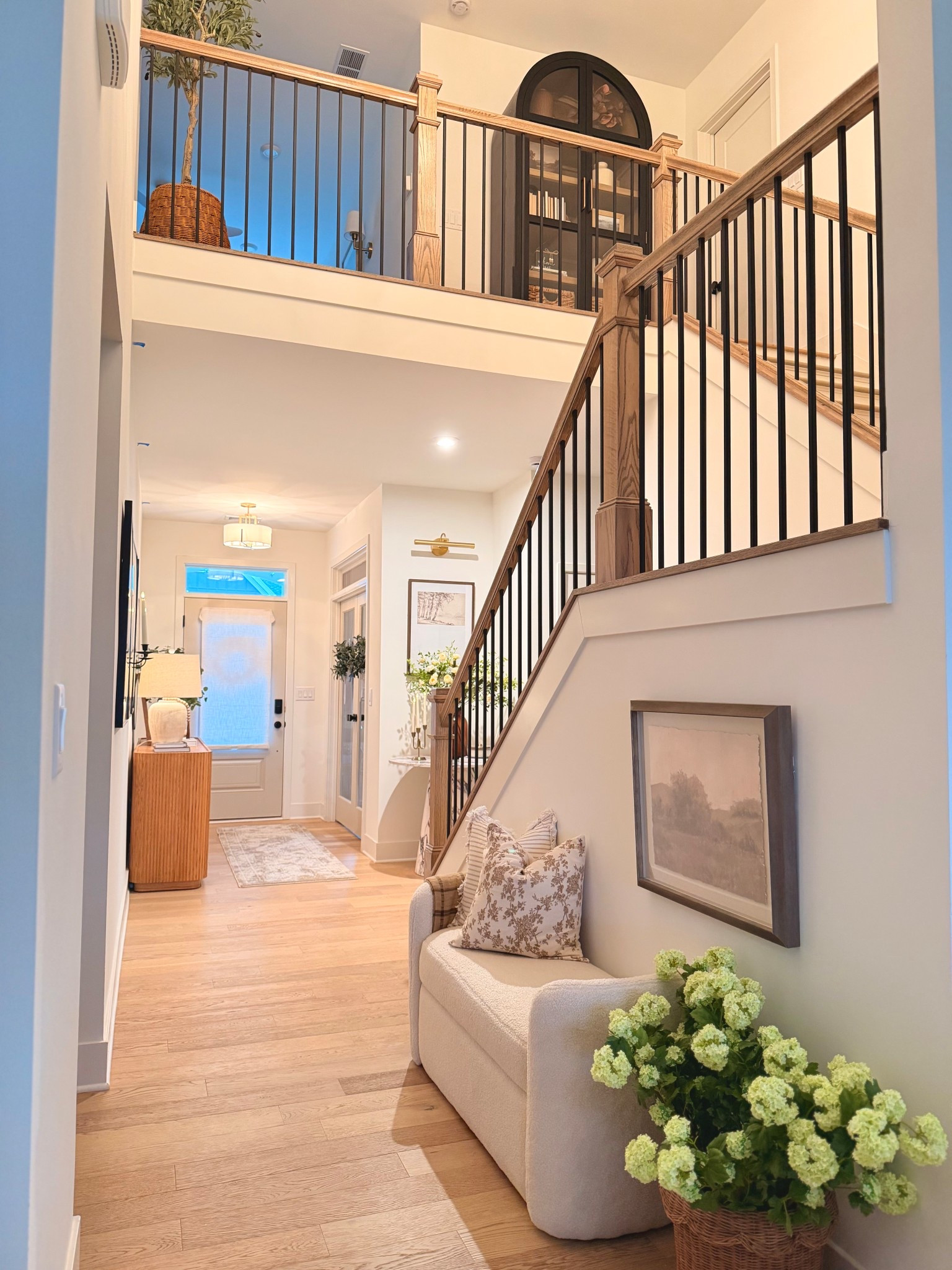I wanted this space to feel warm, welcoming, and layered from the second you walk in. The light wood floors paired with the black stair balusters give that modern contrast, while the soft neutrals, vintage-inspired art, and cozy accent chair keep it timeless and inviting.

A few simple styling pieces textured pillows, a woven basket planter, and warm brass lighting truly elevate the everyday. 

#LTKOver40 #LTKdayinmylife #LTKHome