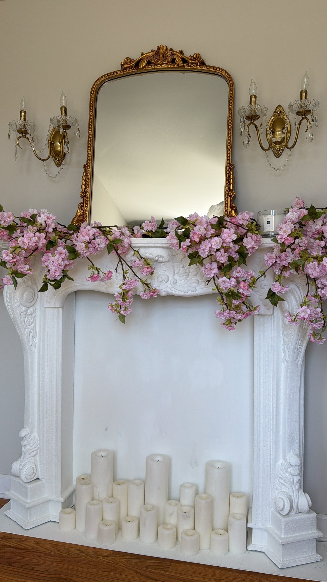 I painted this fireplace mantle with white chalk paint. Brass crystal sconces, pilllar candles, pink cherry blossom stems.

#LTKSaleAlert #LTKHome