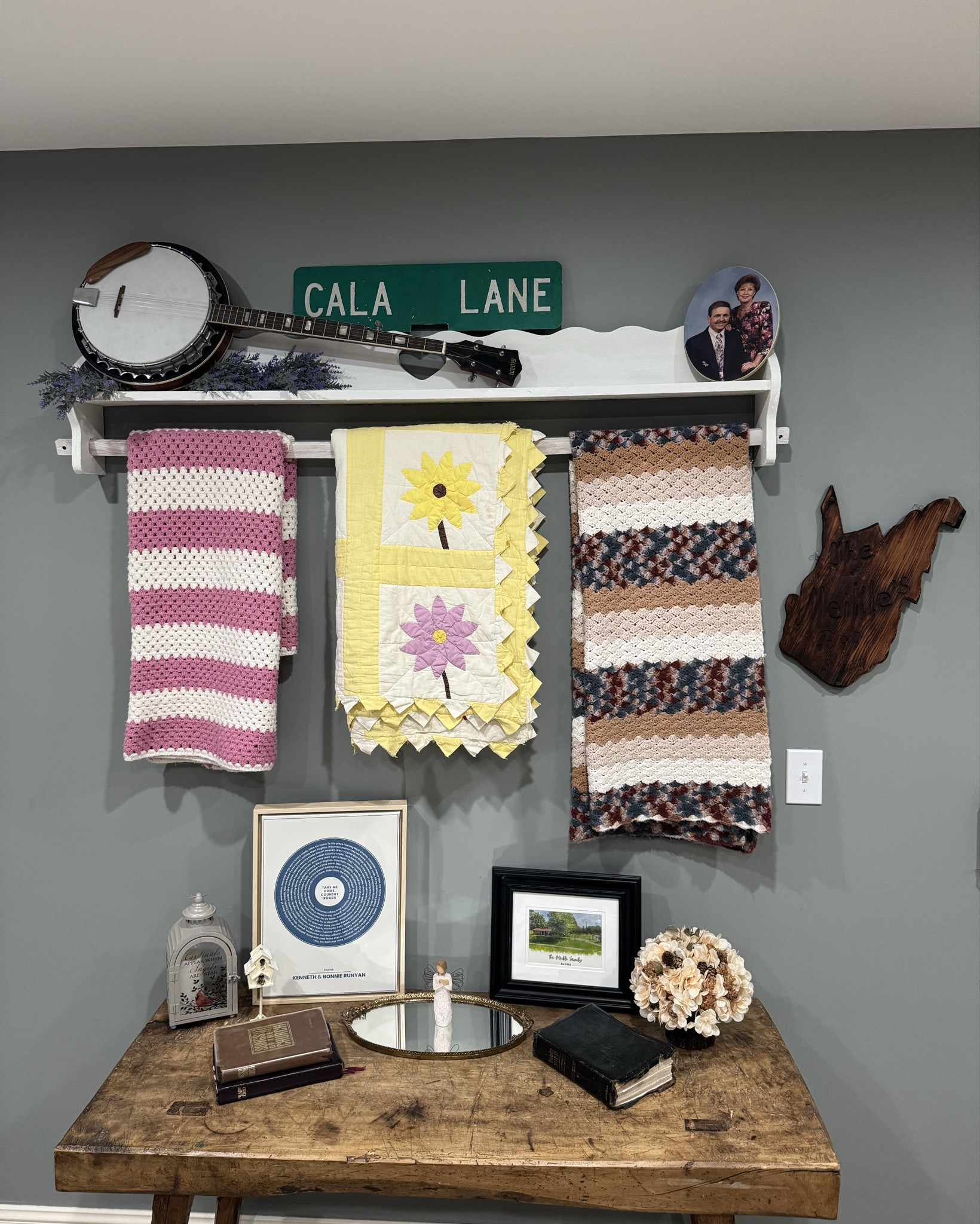 Cala Lane ✨

This is my family in a mood board on a wall…. It’s still a work in progress… but so far this is what I have…. 

Emotional explanation of this wall coming…… 🤷‍♀️🙏

I’ll start at the top:
the Cala Lane sign is indeed a real street sign that was the name of the street my grandparents lived on. 
After the Lord called them both home, I no longer felt a sense of “home” so to speak…. Which is a huge can to unload…. but last year for my 32nd bday I saw Lainey Wilson at the Charleston civic center (which is where I went to my first concert with my mama Bonnie and mom to see Toby Keith 🤠) and then we drove by my grandparents house and just pulled up on the corner of the street and I had my boyfriend jump up and hit it down with a hammer- I was the lookout… decked out in concert attire on the street corner in the holler of Alum Creek, West Virginia. 

Next is mama’s quilt rack, that I painted with annie sloane paint, it was originally a light brown color but I wanted it to pop against the dark wall so I gave her a glam up. All of the quilts were made by either mama or my great grandmother. 

- The banjo resting on the quilt rack is my papa Bobs. He not only played the banjo but he also loved bluegrass music. I can still hear and see him sitting around the kitchen table playing cards with me singing along (terribly but full of spirit). I also hear him singing along in the car, while he taught me how to drive in the Alum Creek church of Christ parking lot and him being silly letting his teeth pop out while giving instructions. (Middle right is a wooden WV state sign with “the Meikle’s” etched on it. )

- Papa Kenneth’s songs of the church hym books. He was a song leader at the church of Christ. So him walking around singing hymns was the typical. 
Sunday mornings listening to him go through what he was going to sing while I got ready…”Cala what would you like to sing today…”
Family trinkets on table: His harmonica and her vanity mirror she kept her perfume on 🎶

Things im adding: papa Kenneth’s guitar, his fiddle, mama’s Bible. 


TBC….. 

#LTKFamily #LTKWedding #LTKHome