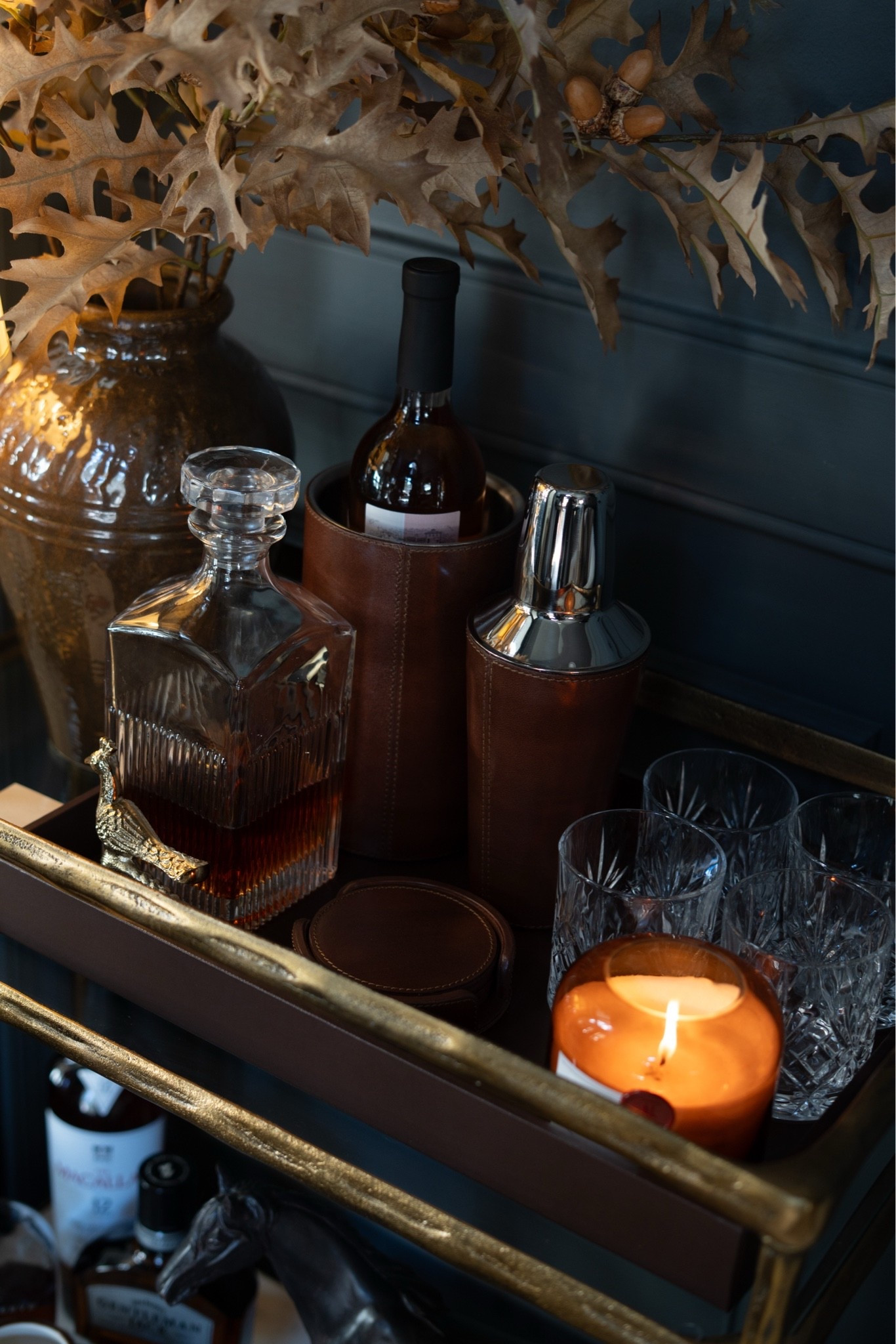 Guys, I just redid my bar cart with the modern heritage aesthetic and I'm absolutely LOVING it! A brass bar cart, leather wine bucket and cocktail shaker, a crystal decanter, cut crystal glasses, and a cordless brass lamp with a pleated shade. Add faux oak leaf stems with acorns and a glowing candle, and it's pure cozy fall bar cart styling. 🍂🥃

#barcart #barcartstyling #falldecor #modernheritage #falldecorideas #homebar #cozyhome