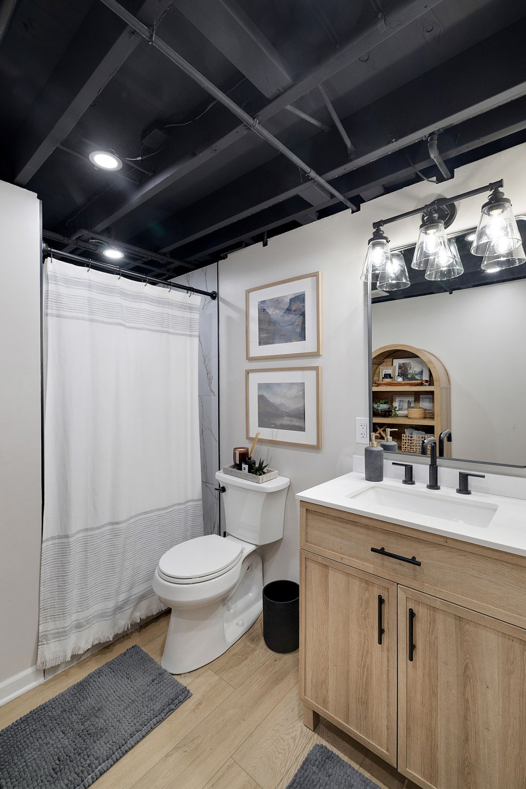 Our challenge in this basement bathrooms was countering the existing black and white that can sometimes come across as stark.  Working with an existing vanity, we brought warmth in with an additional light wood armoir that adds functionality for linen storage and space.  Layers of greenery, landscape prints, and natural, woven textures, it feels much less like a basement and more like a spa like retreat.  

 #LTKHome #LTKFindsUnder50 #LTKStyleTip