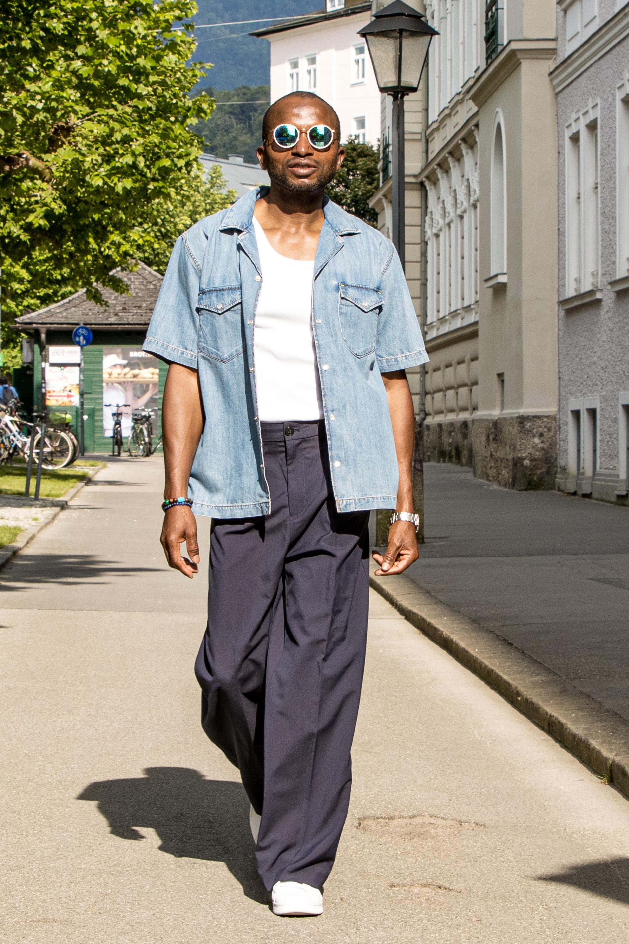 The navy blue wide-leg pants are made of a high-quality, lightweight fabric that provides a comfortable fit. These pants have a relaxed fit from the waist to the ankles, creating a chic and trendy silhouette. The deep navy-blue colour makes the overall look more sophisticated.
The denim shirt with short sleeves is made of soft, medium-wash denim. It has a classic collar and buttons down the front, so it can be styled in many different ways. A relaxed and slightly oversized fit, the shirt provides a casual and effortless feel. The denim fabric imparts a sense of ruggedness and texture to the ensemble.
Under the denim shirt is a crisp white tank top. The tank top is made of a light and breathable material that keeps you comfortable all day. It has a slender shape that looks good on anyone and can be used as a base for other clothes.
An additional pair of white sneakers complete the outfit. These sneakers have a clean and simple design and a comfortable sole. They are made from durable materials, which allow for long-lasting wear and versatility in various casual settings. The white colour of the sneakers makes the look fresh and young.
This ensemble is a stylish and contemporary outfit that effortlessly blends comfort and fashion. It's great for a lot of different things, like casual gatherings, shopping trips, or even a day out in the city.


#LTKmens #LTKstyletip #LTKfamily