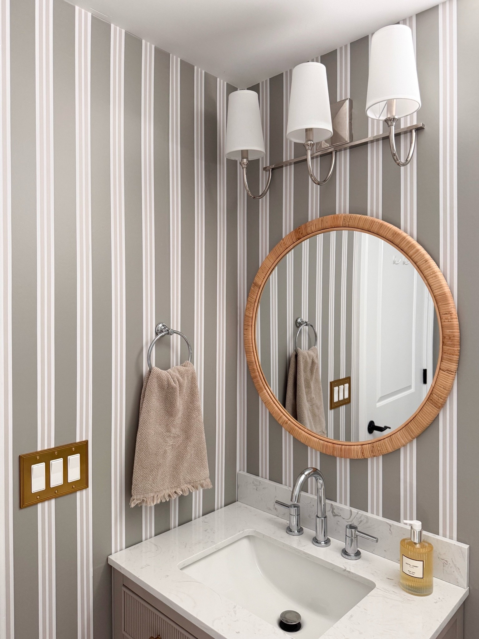 This powder room is such a great example of how wallpaper can completely transform a small space. The striped wallpaper, woven mirror, warm brass details, and classic lighting create a look that feels fresh, timeless, and full of character.

powder room decor, bathroom wallpaper, striped wallpaper, small bathroom ideas, powder room inspiration, woven mirror, bathroom design, brass bathroom fixtures, timeless home decor, coastal home style, bathroom makeover, girlonthehudson

#LTKHome #LTKdayinmylife #LTKSeasonal