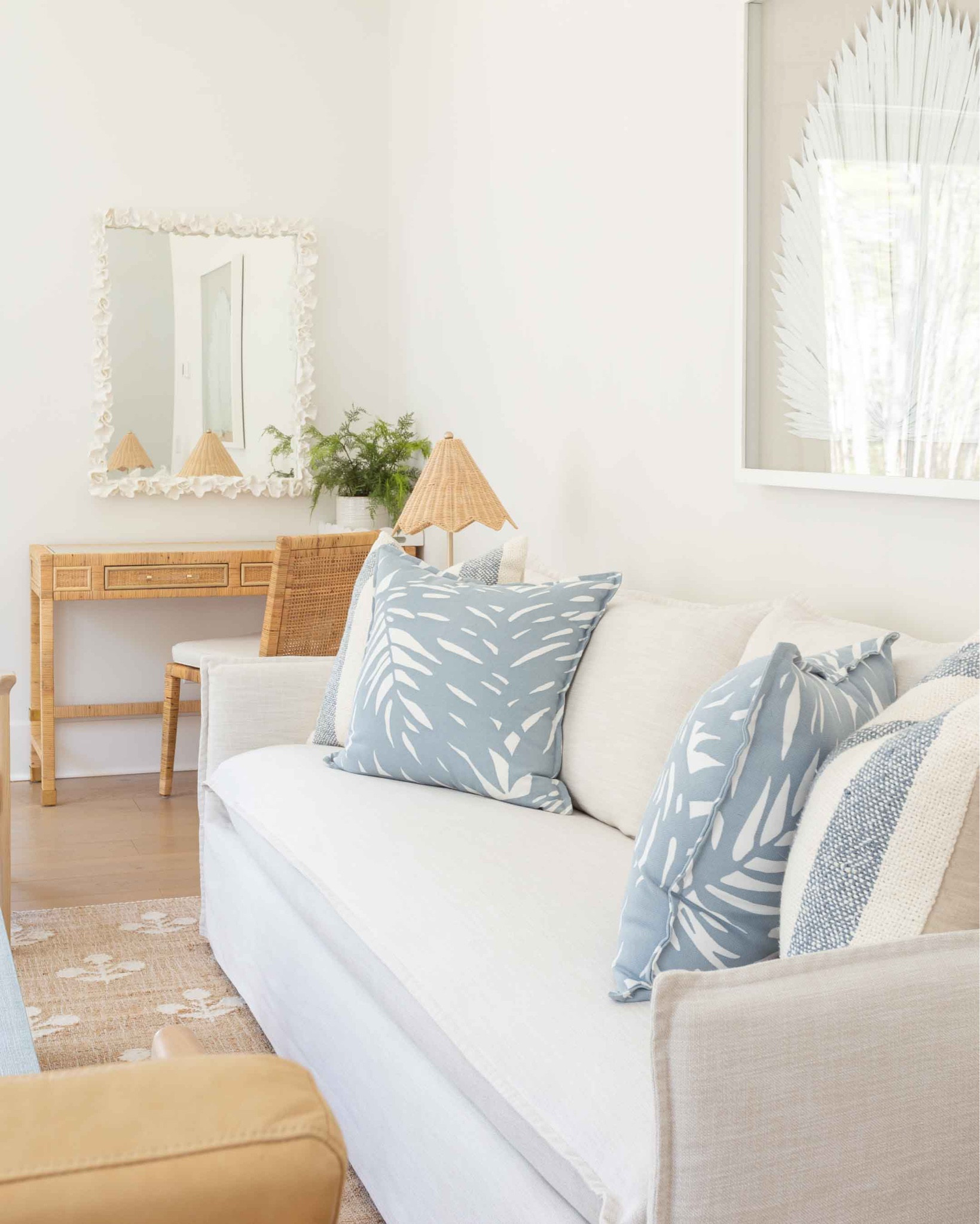 Our Florida carriage house living room features a slipcovered indoor/outdoor sofa, camel leather chairs, block print rug, a light blue coffee table, scalloped rattan lamps, round side tables, oversized palm art, and light blue tropical pillows! I love our white coral mirror hanging over this affordable rattan desk, too! Take the full tour here: https://lifeonvirginiastreet.com/our-florida-carriage-house-tour/.
.
#ltkhome #ltkseasonal #ltksalealert #ltkfindsunder50 #ltkfindsunder100 #ltkstyletip #ltktravel #ltkover40 coastal living room decor, Serena & Lily style, coastal grandmillennial, coastal grandmother aesthetic 

#LTKsalealert #LTKSeasonal #LTKhome