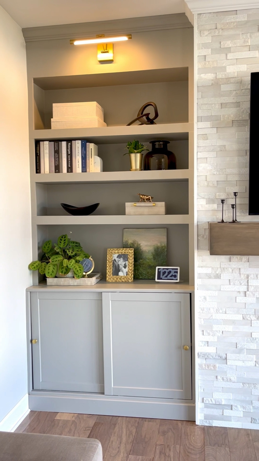 Living room fireplace wall, tv wall, fireplace with shelves and storage on both sides.  Living room decor, picture lights, stacked marble tile, open shelf decor, stacked stone mantle 

#LTKFind #LTKstyletip #LTKhome