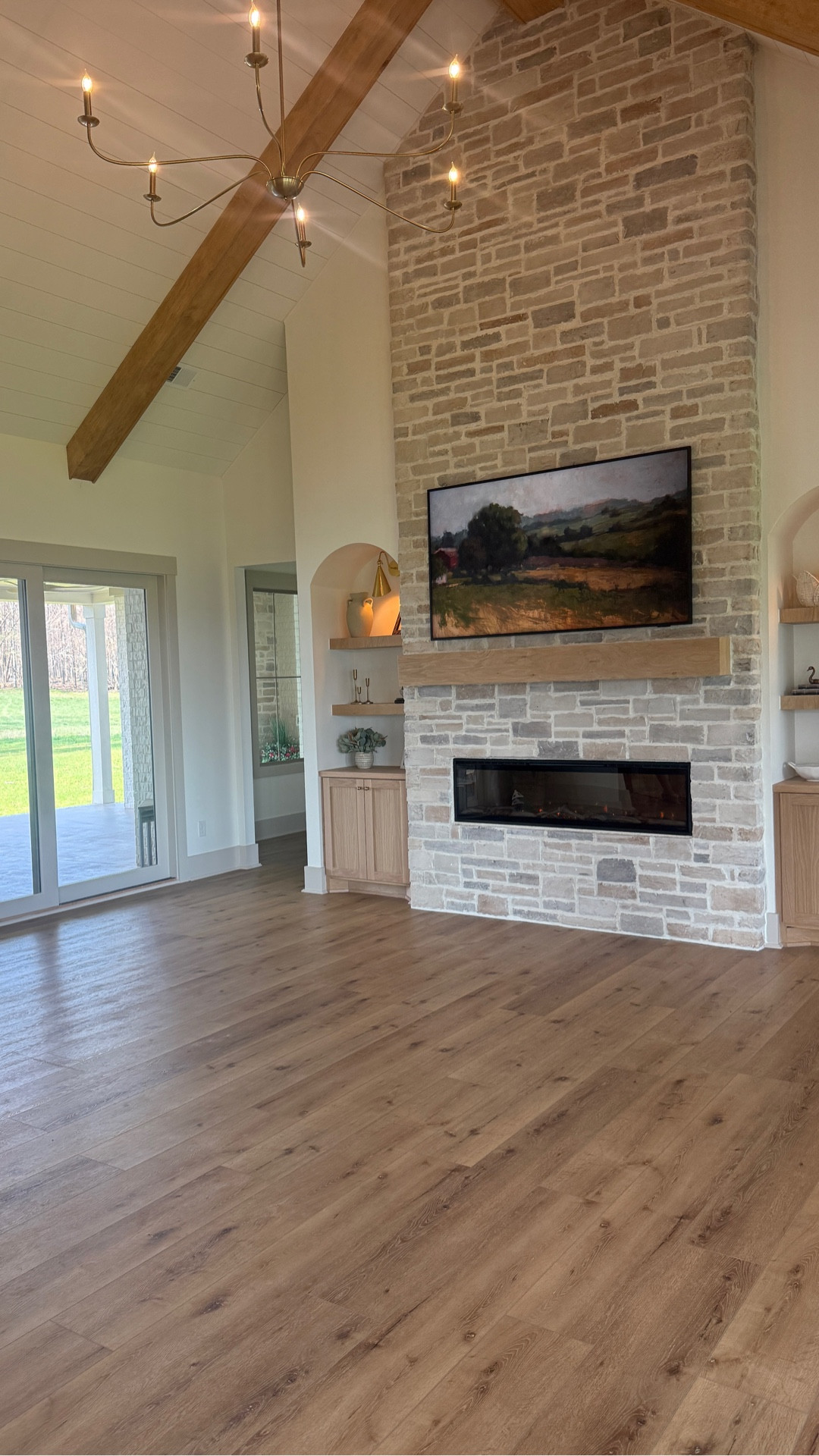 New build | interior design | living room | stone fireplace | white oak cabinets | white oak mantle | Samsung frame tv pro | tulip basket | target home | taper candle holders | dimplex fire place | electric fireplace | living room shelves | home decor | home inspo | shelf decor | vases | bowls | Swans | sconces | Wayfair light fixtures | brass sconces | studio McGee | wood beams | Shiplap ceiling | maple wood beams | outdoor patio | modern farmhouse | cabinet hardware | linear fireplace |  coretec Cairo oak floors | LVP floors | accessible beige paint | alabaster paint | modern organic home | chandelier | light fixtures | brass sconces | Wayfair home | LTK home | Samsung frame tv | arch shelves | built in shelves | @Wayfair 

#LTKHome #LTKmomlife #LTKvlog