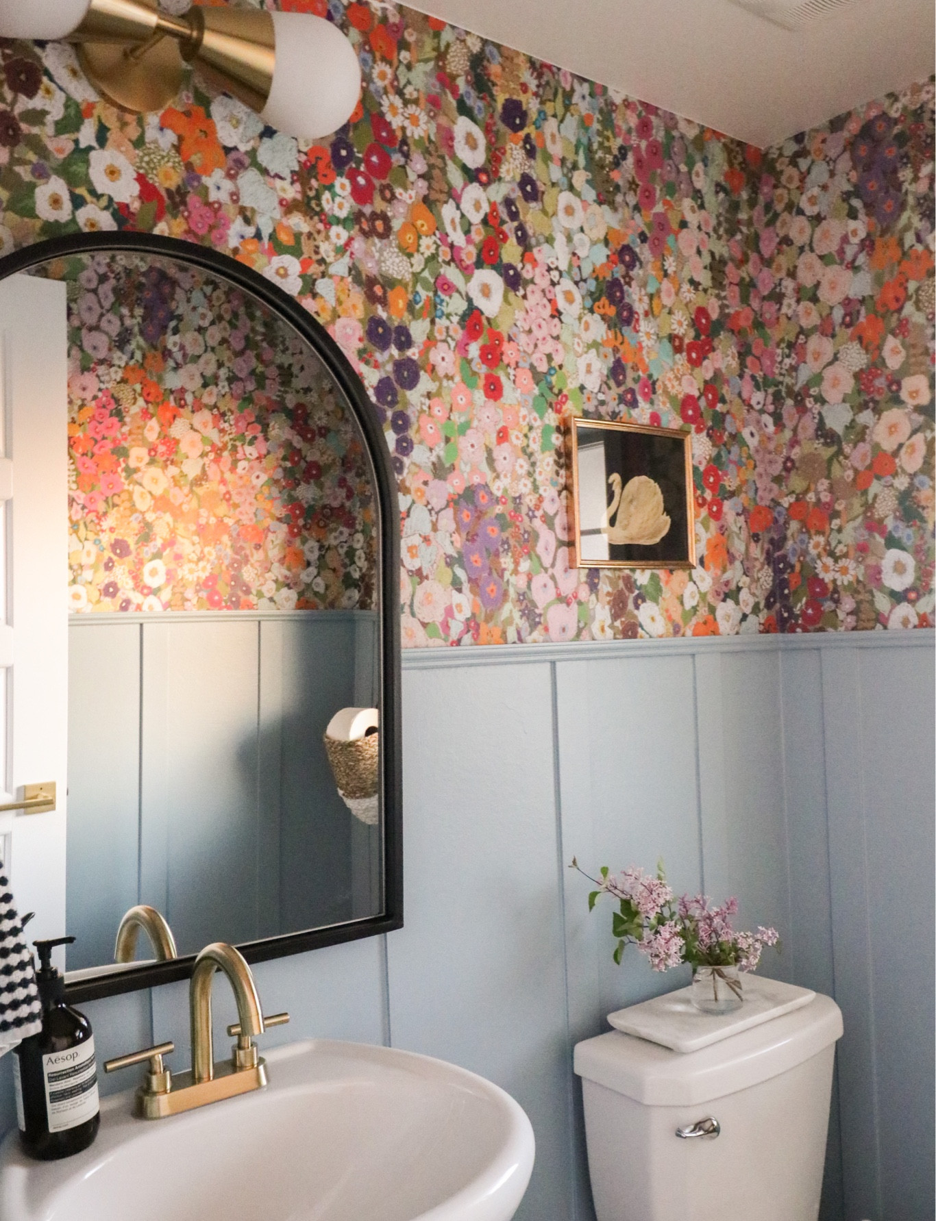 Colorful powder room bathroom redesign update. Board and batten walls, hollyhocks wallpaper, brass hardware, marble accents, baskets for storage 

#LTKunder50 #LTKhome #LTKunder100