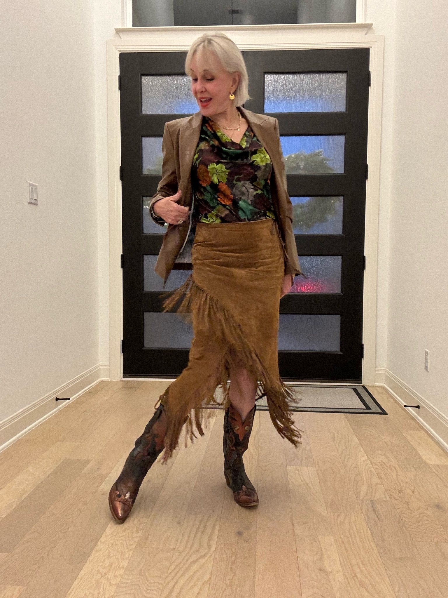 this luxurious draped-neck blouse in stretch silk satin charmeuse. Its ten-color oak and maple leaf print honors the season with fresh whimsy.
Skirt
Suede leather fabrication 
Sheath wrap silhouette
Buck stitching detail
High rise waistline 
Front slit opening on hem
Suede fringe hemline
Fully lined
Lucchese western boots in brown 
Brown faux leather blazer/ jacket