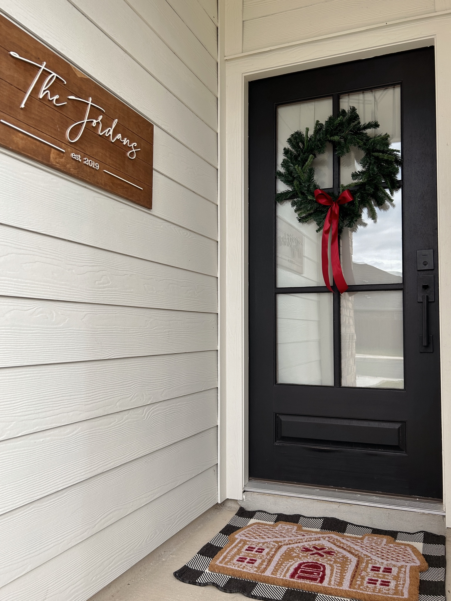 The beginning of our Christmas porch. 🖤🌲🎀
This wreath was only $10, but with the addition of a big red bow, you’d never know it! 
I used the 24” wreath on my front door & two 18” wreaths on my front window. I linked the suction cup hooks I use every season to add wreaths to my window as well as our reversible rug, Christmas lights, & light clips. The gingerbread door mat was an HEB find but I linked something similar. Merry Christmas! 🎅🏼
