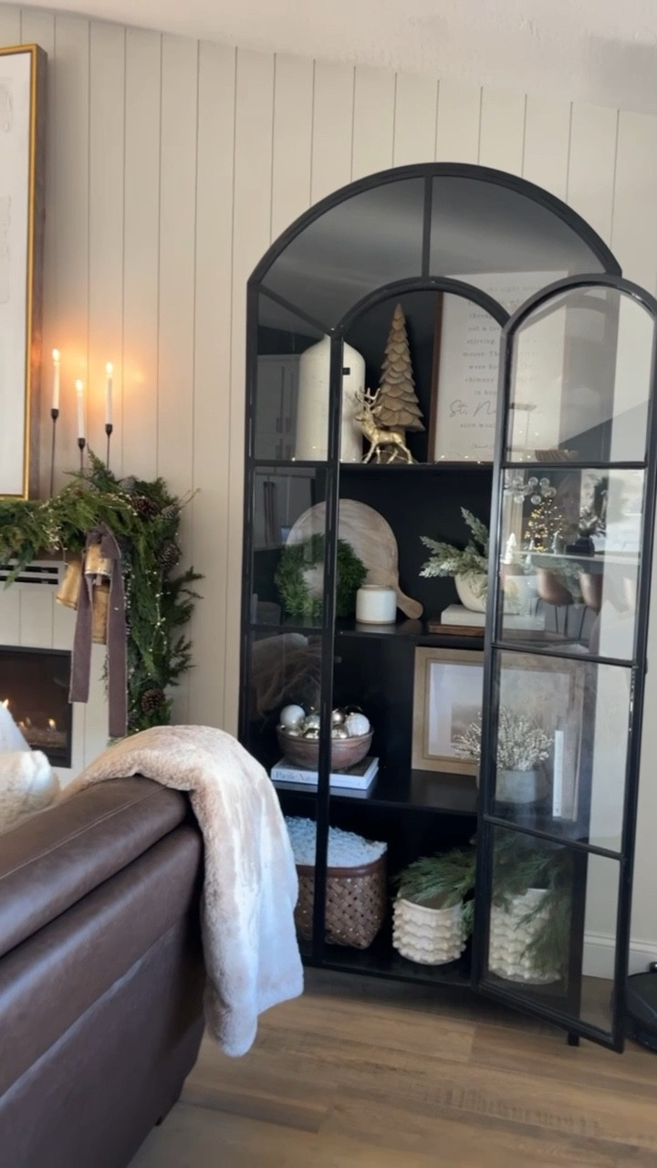 🎄Linking similar items and sharing some Christmas Cabinet Styling Tips! I got my cabinet from Grove Collective but I wasn’t able to link it here but I’ve linked one from Crate and Barrel. 

* 	Theme-Based Decor: Choose a cohesive theme for your cabinet shelves, such as rustic, traditional, or modern. Use decorations like miniature Christmas trees, wreaths, festive figurines, small frames with a holiday print/winter scenery or holiday-themed candles that align with your chosen theme. 🎅🏻

* 		Balance and Symmetry: Arrange items with balance and symmetry to create an aesthetically pleasing display. Mix varying heights and textures, placing taller items at the back and shorter ones at the front. This creates a visually appealing arrangement that draws the eye. I love using books to add height and interest. I have some of my favorite home decor books linked to my LTK shop but you can use a variety of book options depending on your theme. It would be so fun to incorporate holiday children’s books if it aligned well with your colors! I also like using wooden cutting boards to add height as well as for the added warmth the wood tones bring. 😌 📚 

* 		Add Warm Lighting: Incorporate warm LED lights or string lights to add a cozy and festive glow. Strategically place the lights among the decorations to highlight specific items and create a warm ambiance.✨

*             Also transform your pots and bowls by jazzing them up with ornaments or faux pine branches! It’s like giving your planters a holiday hug. 🌲


*          Also think about functionality if you need storage! Add a pretty basket and throw your blankets or items you need tucked away in there.  If you don’t want those items seen just make sure the basket is deep enough and not see through. 😉 🧺

👀 Look around your home first! You probably have items you can easily incorporate into your shelves display! 
.
#shelfie #shelfstyling #cabinetstyling #christmasdecorations #2023christmas #neutralchristmas #modernchristmas #traditionalchristmas 

#LTKHoliday #LTKSeasonal #LTKhome