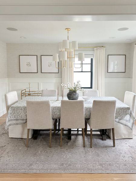 Dining room design. Neutral dining room. Cold chandelier with shades. Gallery frames from pottery barn in gray wash finish. Floral prints. Vicki and Cole tablecloth. Block print tablecloth and Blue. Upholstered chairs. Curtains. White drapes. Grass cloth wallpaper. Wainscoting.

#LTKsalealert #LTKhome #LTKstyletip