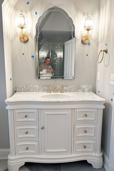 Besides some paint touch ups this bathroom is complete! White French vanity with marble top arched wall mirror gold sconces #bathdesign #bathremodel 

#LTKsalealert #LTKmidsize #LTKhome