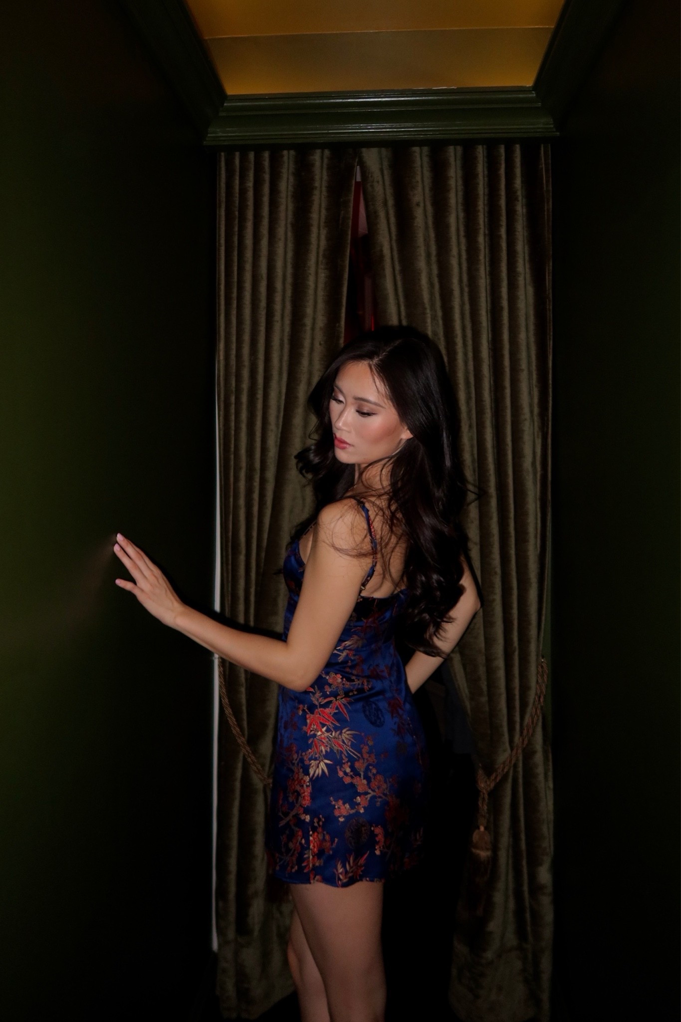 the realisation par shanghai nights mini dress in size small — a navy satin mini dress with a red cherry blossom and bamboo oriental print, fitted bodycon silhouette, and open back with delicate strap detail — styled with soft waves and a deep red lip for a sultry night out. the rich satin print and figure-skimming silhouette make this the ultimate dark feminine occasion dress. perfect for nyc cocktail bars, candlelit date nights, lunar new year celebrations, and going-out evenings. shop this look linked above.