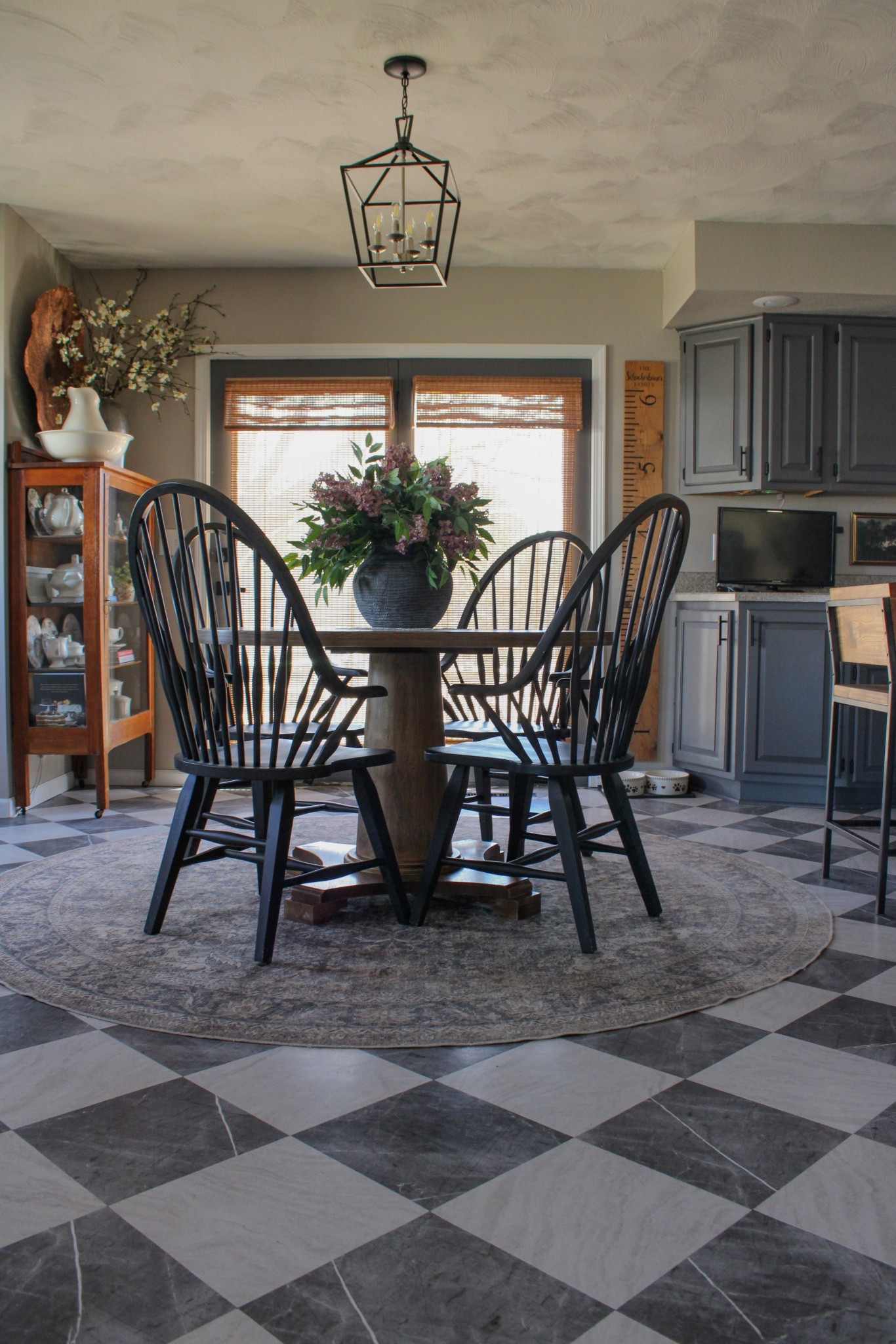 Traditional Farmhouse Dining Room featuring peel & stick floor tiles, round machine washable rug, round solid wood pedestal dining table, black windsor dining chairs, bamboo woven blinds, modern farmhouse lantern pendant, dining cabinetts

#LTKHome