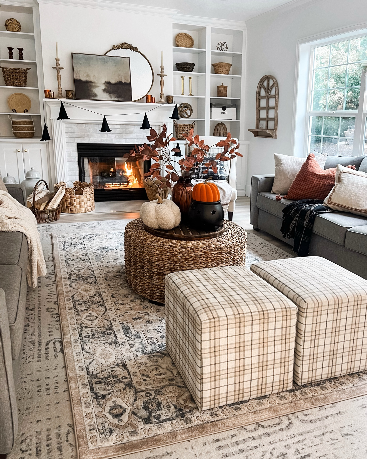A cozy fall/autumn living room. A modern cottage fireplace with a lovely rug, pillows, cubes and pumpkins. 

#LTKSeasonal #LTKHome #LTKFallSale