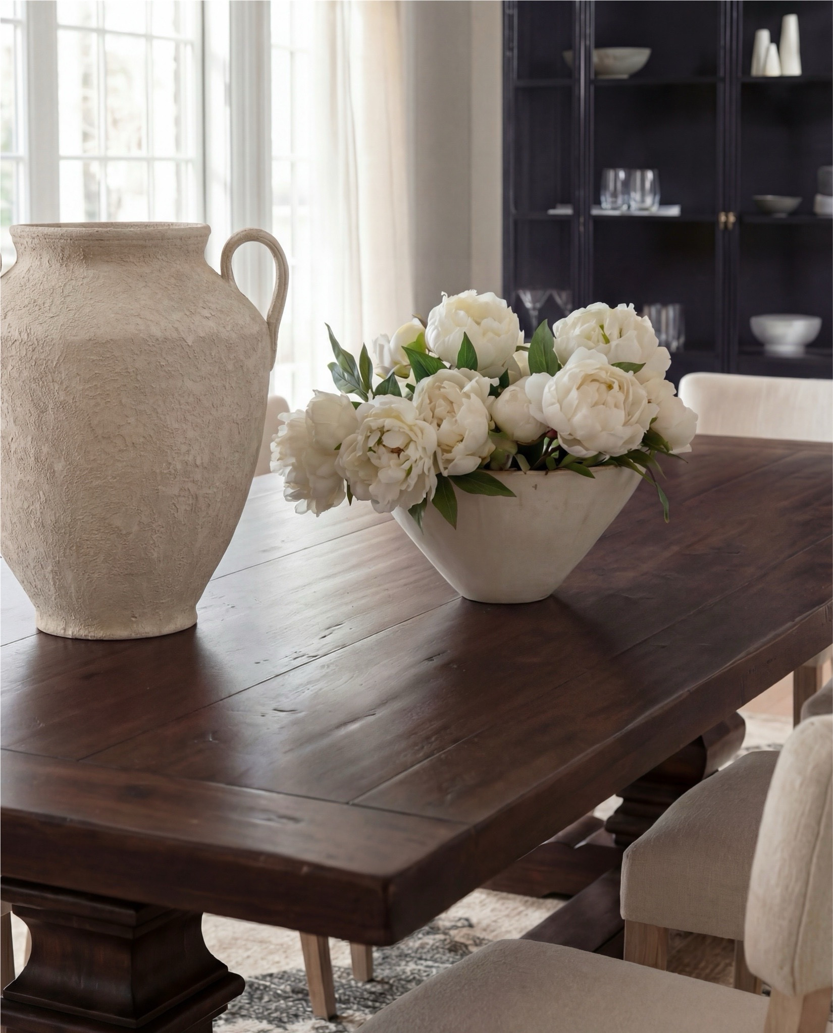 Shop the Look:
• Dark wood pedestal dining table
• Cream upholstered dining chairs with light wood legs
• Large neutral area rug with charcoal medallion pattern
• Black arched display cabinet / hutch
• Light wood sideboard / buffet cabinet
• Large ceramic floor vase (neutral tone)
• White ceramic bowl with white florals (peonies or roses)
• Pink faux cherry blossom stems in white vase
• Neutral ceramic table lamp with white shade
• Tall brass wall sconces with glass detailing
• Framed botanical artwork (set of four)
• Dark abstract wall art (large statement piece)
• White decorative vases (assorted sizes)
• Light linen curtains

#LTKHome #LTKSaleAlert