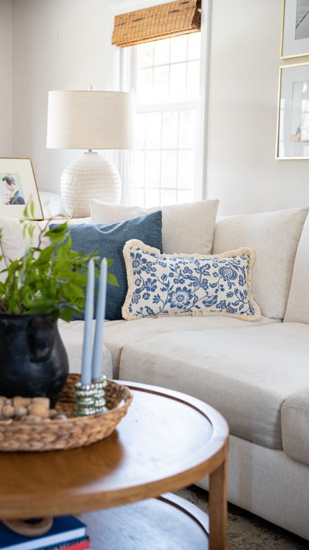 Give your living room a summer upgrade with some decorative blue and white pillows, blue candlesticks, living room home decor. Coastal style home, decor, white couch, roun wooden coffee table, large lamps, artificial plants, and more.

#LTKHome #LTKFamily