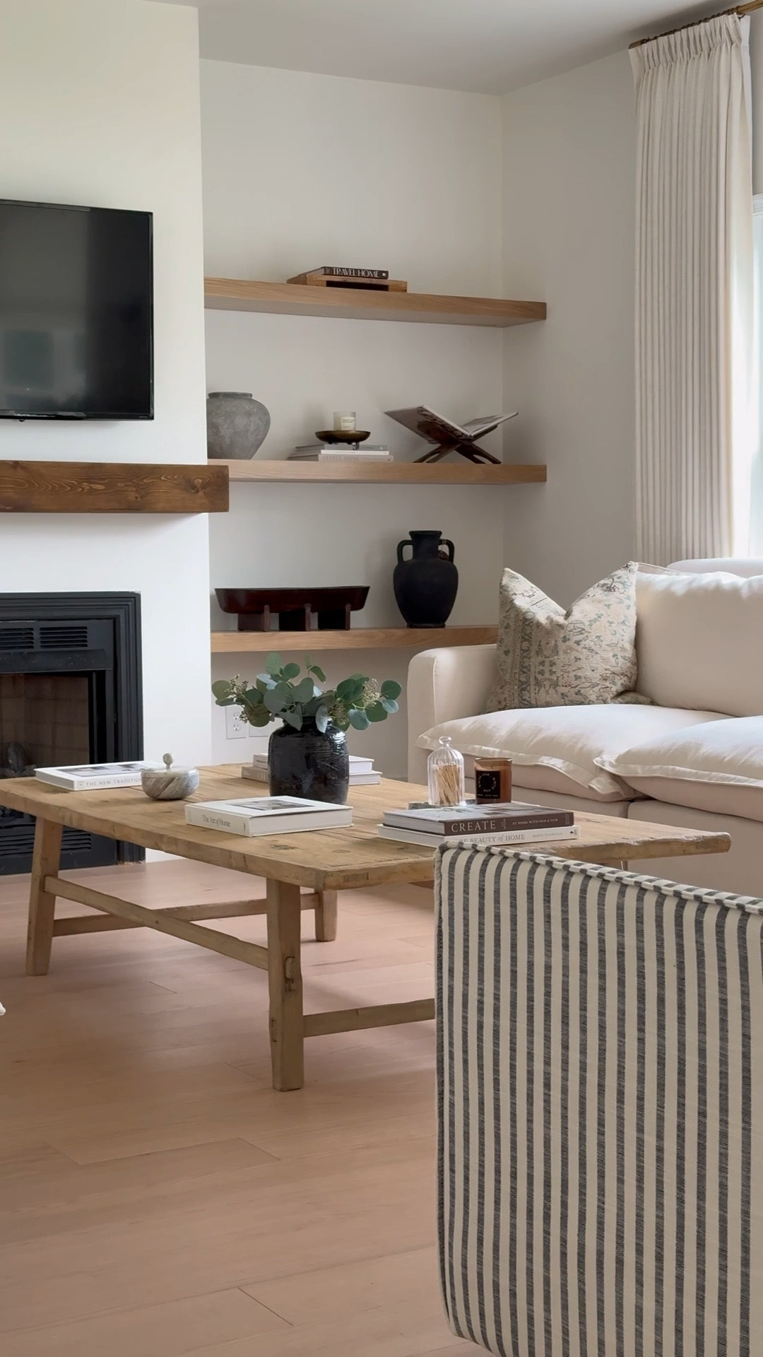 Living room styling transitioning from summer to fall 🤎 vintage inspired coffee table, striped arm chairs, reclining sofa, floating shelves, curtains ! 

#LTKFallSale #LTKSeasonal #LTKHome