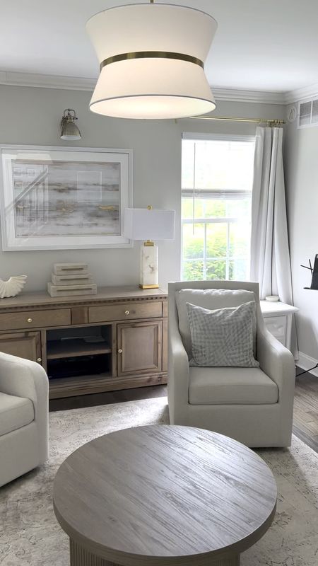 New living room swivel chairs, shaded brass chandelier pendant light and round wood coffee table 

#LTKOver40 #LTKHome #LTKSaleAlert