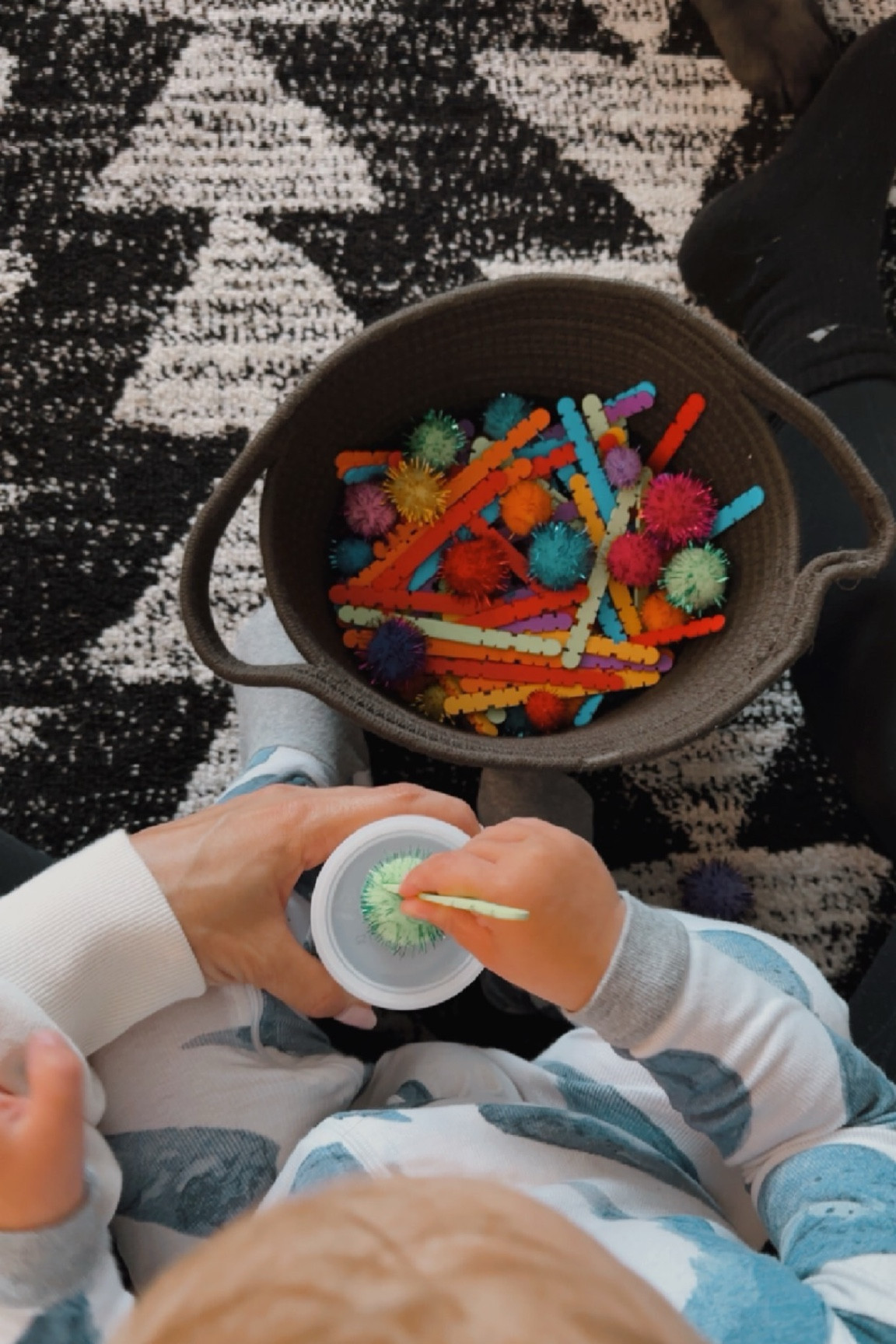 Toddler sensory DIY activity - with popsicle sticks and pom poms!! How to make it: Cut a hole in the top of your puffs lid, put all the pom poms and sticks in a basket & let them have fun!! 

#LTKkids