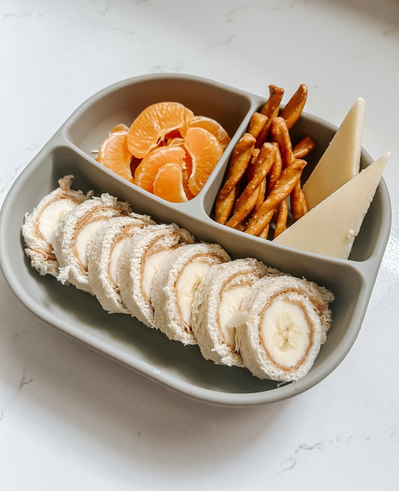 Sharing more plate inspo in 2026, for the kiddos and adults! My four year old has been on a PB&J kick for what seems like months now, so I’m trying to find ways to switch it up…enter peanut butter banana roll! Roll out a piece of bread, smear on a layer of peanut butter, then cut the banana to the length of the bread. Roll it up and cut into slices! I also like to add things like cinnamon, honey, or hemp hearts to the inside as well! 

I served this with Dots pretzels, Tillamook sharp cheddar, and a cutie! This is a plate he will eat every single bit of!

These Isla Plates from Calla & Friends are my favorite for meal time. They come with a life to make leftovers and travel easy! Use code LITTLEKINGS to save 10%

#lunch #momlife #family #foodie 

#LTKKids #LTKActive