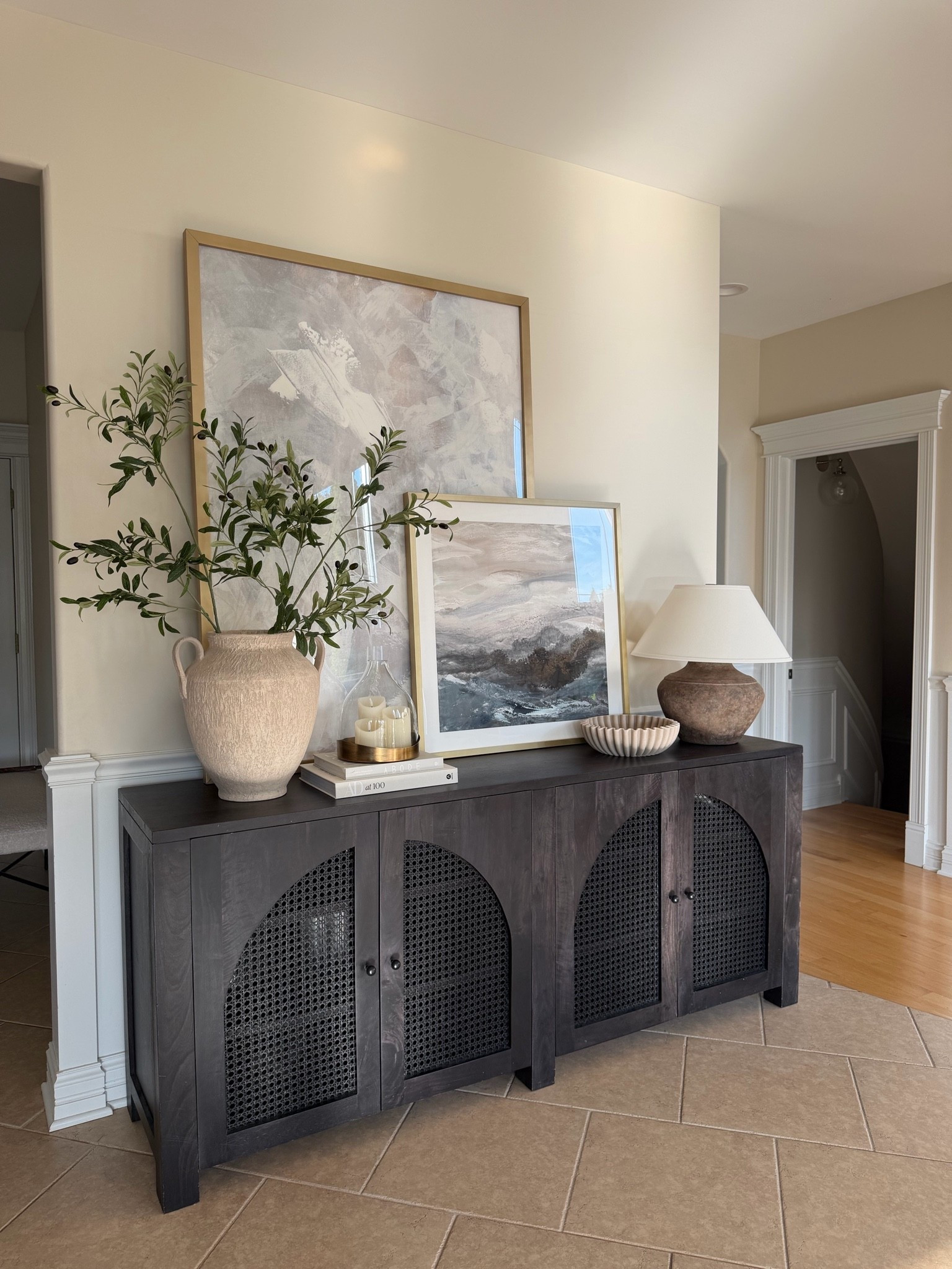One of my favorite styling moments in our home. 🤎 Layered artwork, warm wood tones, soft lighting, and simple decor create a space that feels collected without feeling cluttered. Everything I can link is linked here.

#LTKHome