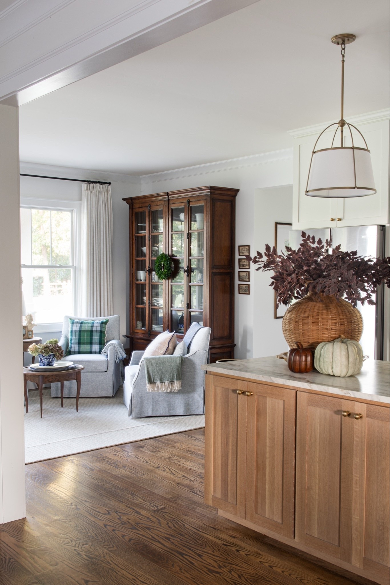 #ad cozy fall sitting room. My favorite pieces come from @Wayfair Thwse blue chairs I’ve had for 4 years and I use them daily, the wool rug and this wooden bookcase that I use as a china cabinet. Touchesbof fall with the stems on the kitchen island and my favorite pendant lights. #wayfair #wayfairpartner #ltkhome #ltkseasonal