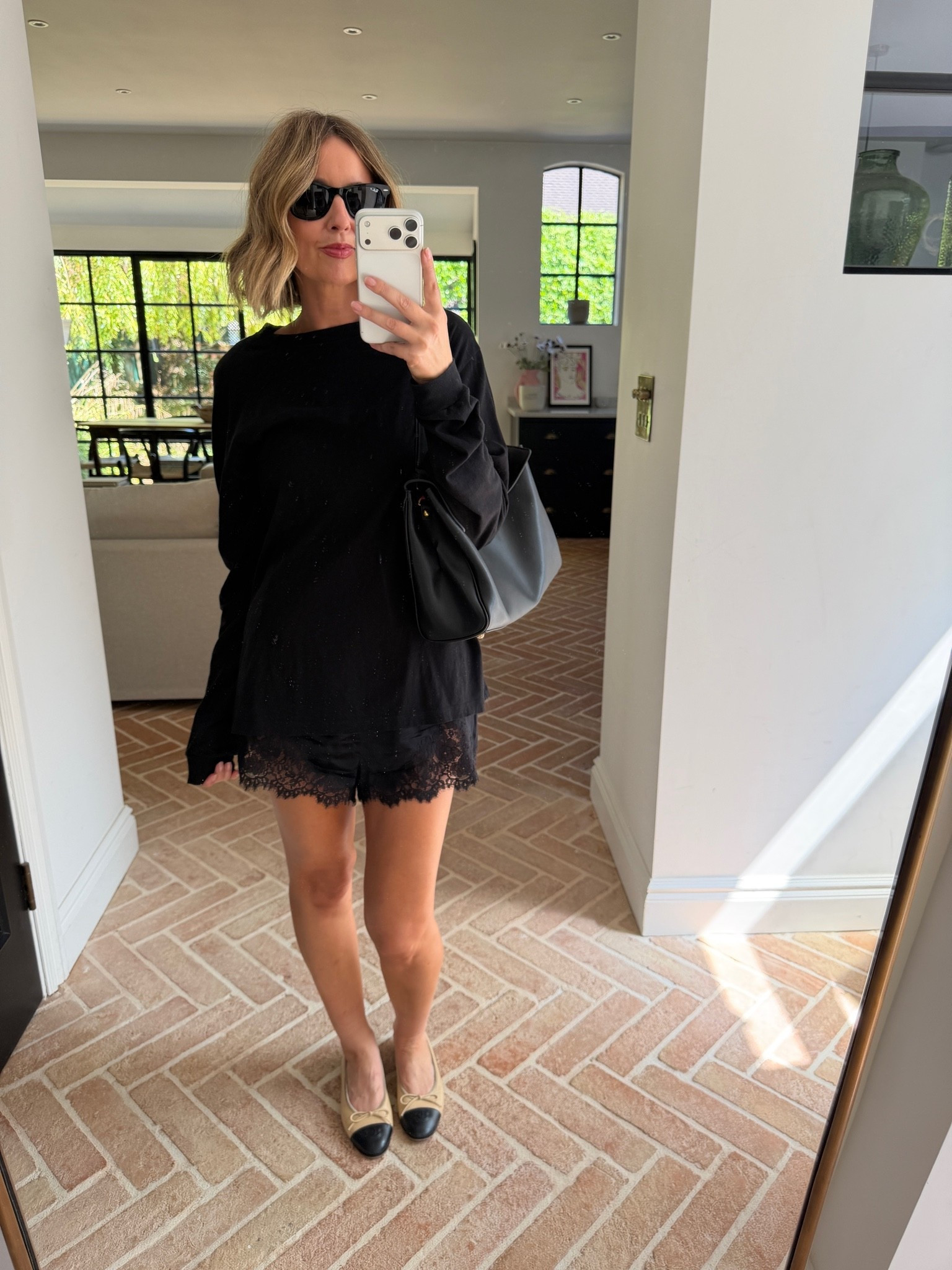 black oversized sweatshirt, black longline sweatshirt, oversized black top, black lace shorts, lace trim shorts, black lingerie shorts, slip shorts, two tone ballet flats, cap toe ballet pumps, Chanel style ballet flats, beige and black flats, black leather tote, oversized black tote, soft leather bag, black sunglasses, all black outfit, tonal black look, lingerie dressing trend, sweatshirt and shorts outfit, how to style lace shorts, elevated casual look, off duty chic, effortless style, quiet luxury casual, mum style, stylish mum outfit, over 40 fashion, ageless style, mirror selfie style, French girl casual

#LTKsummer #LTKdatenight #LTKpartywear