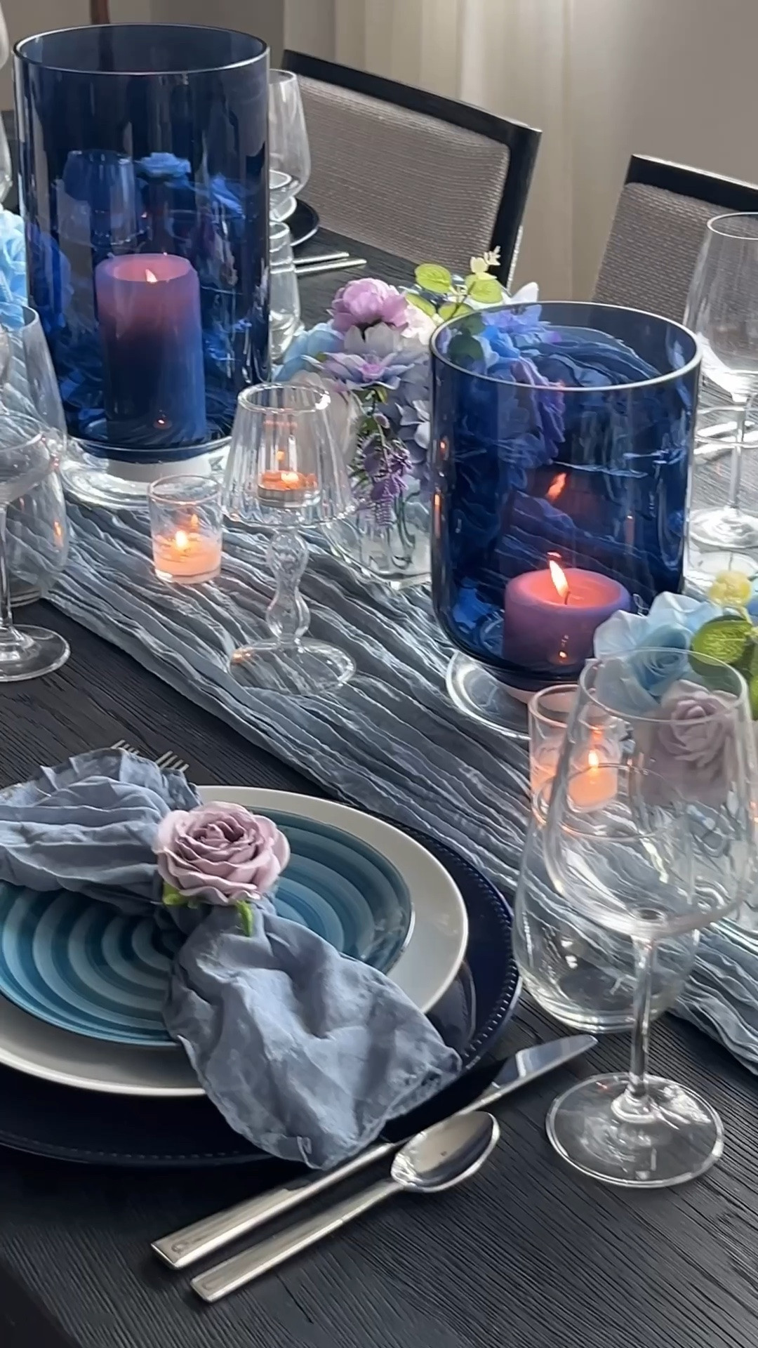 Moody blue Mother’s Day tablescape with tonal blue spiral plates, navy glass hurricanes, candlelight, gauze table runner, layered white and navy dinnerware, floral napkin rings, silver tray, silver salt and pepper shakers, clear wine glasses, pastel florals, blackberry and lime infused water, donut tower dessert stand, modern hosting decor, elegant brunch table, blue and lilac tablescape, elevated entertaining, candlelit dining table, modern hostess inspiration, spring tablescape ideas, layered place settings, black dining table decor, soft blue decor, Mother’s Day brunch inspiration.

#LTKMothersDay #LTKSeasonal #LTKHome