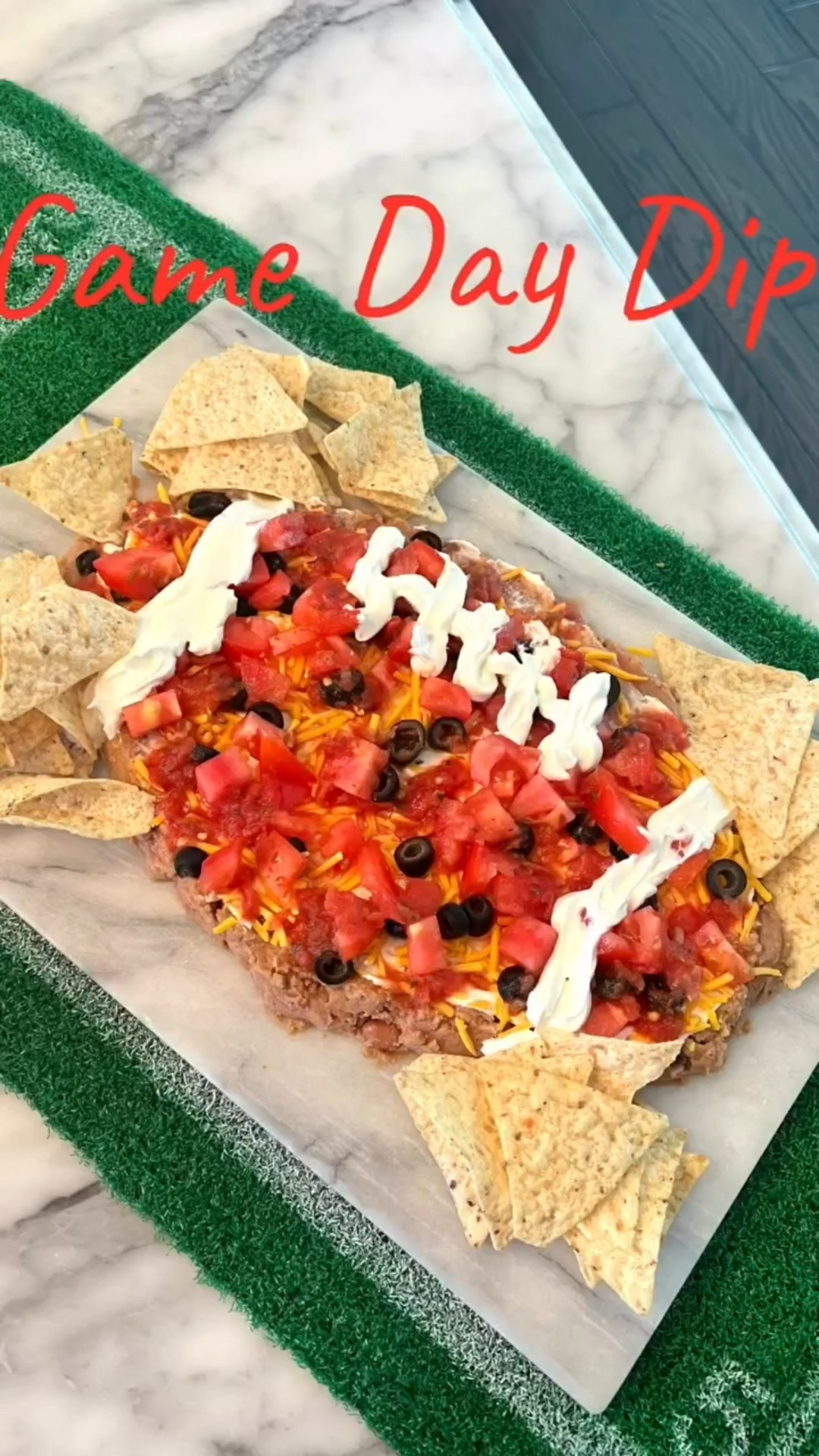 We ready?! I have you covered for a large crowd.  This dip can be created to your desire and used throughout the year.  Save & enjoy! 

Layer: 
2 cans of bean dip 
Sour cream 
Taco seasoning 
Shredded cheddar 
Black olives 
Chopped tomato 
Salsa 
(Not used but optional below) 
Cilantro 
Jalapeños 
Beef 
Pepperjack cheese 
Queso 

Serve with chips. Great for a crowd since you can easily double it. 
~XXAP
