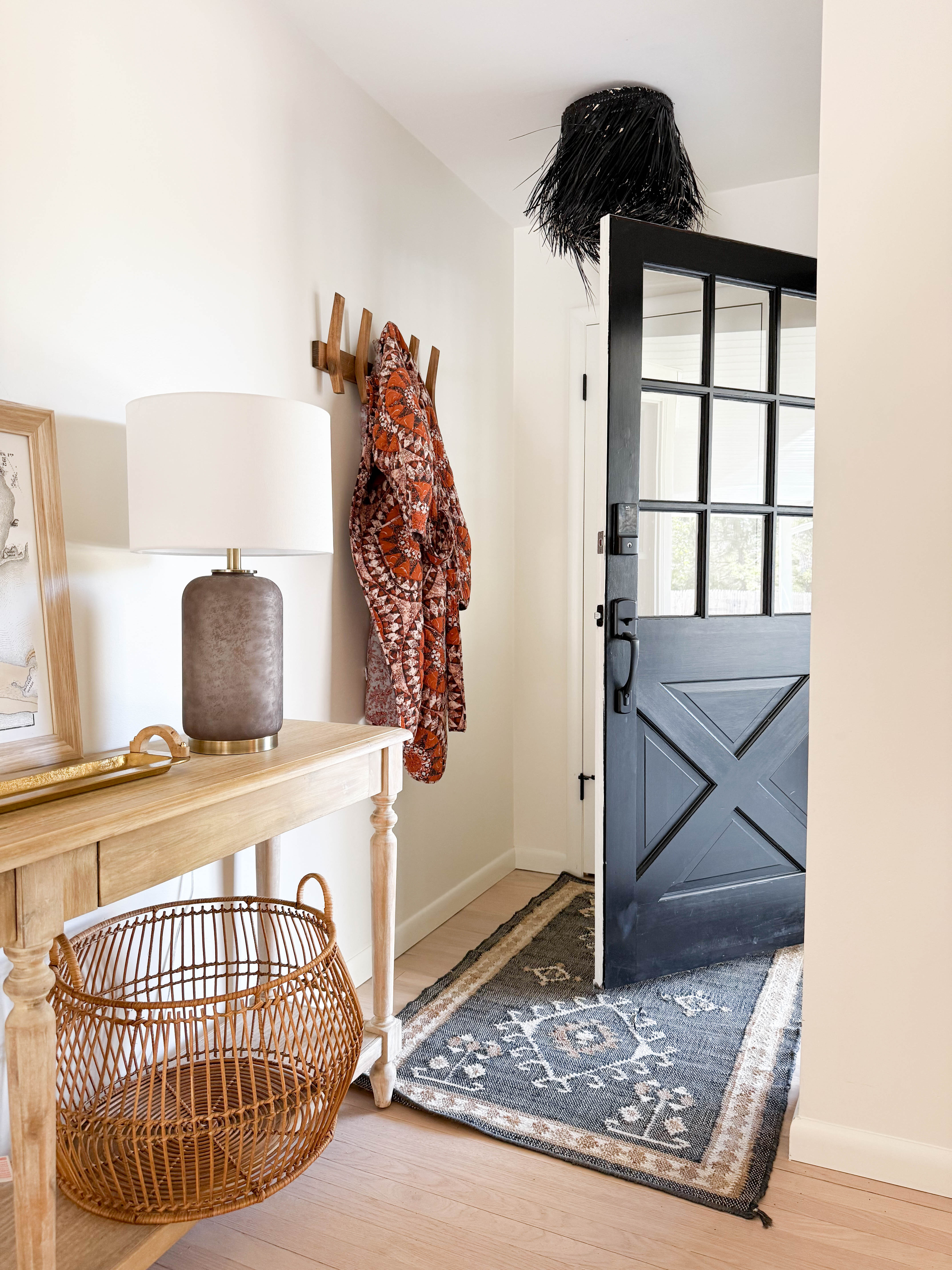 Entryway with a wood console table, black front door, patterned runner, and woven basket. Added a ceramic table lamp and wall hooks by the entry. Linked exact and similar pieces here.

#LTKHome #LTKSaleAlert