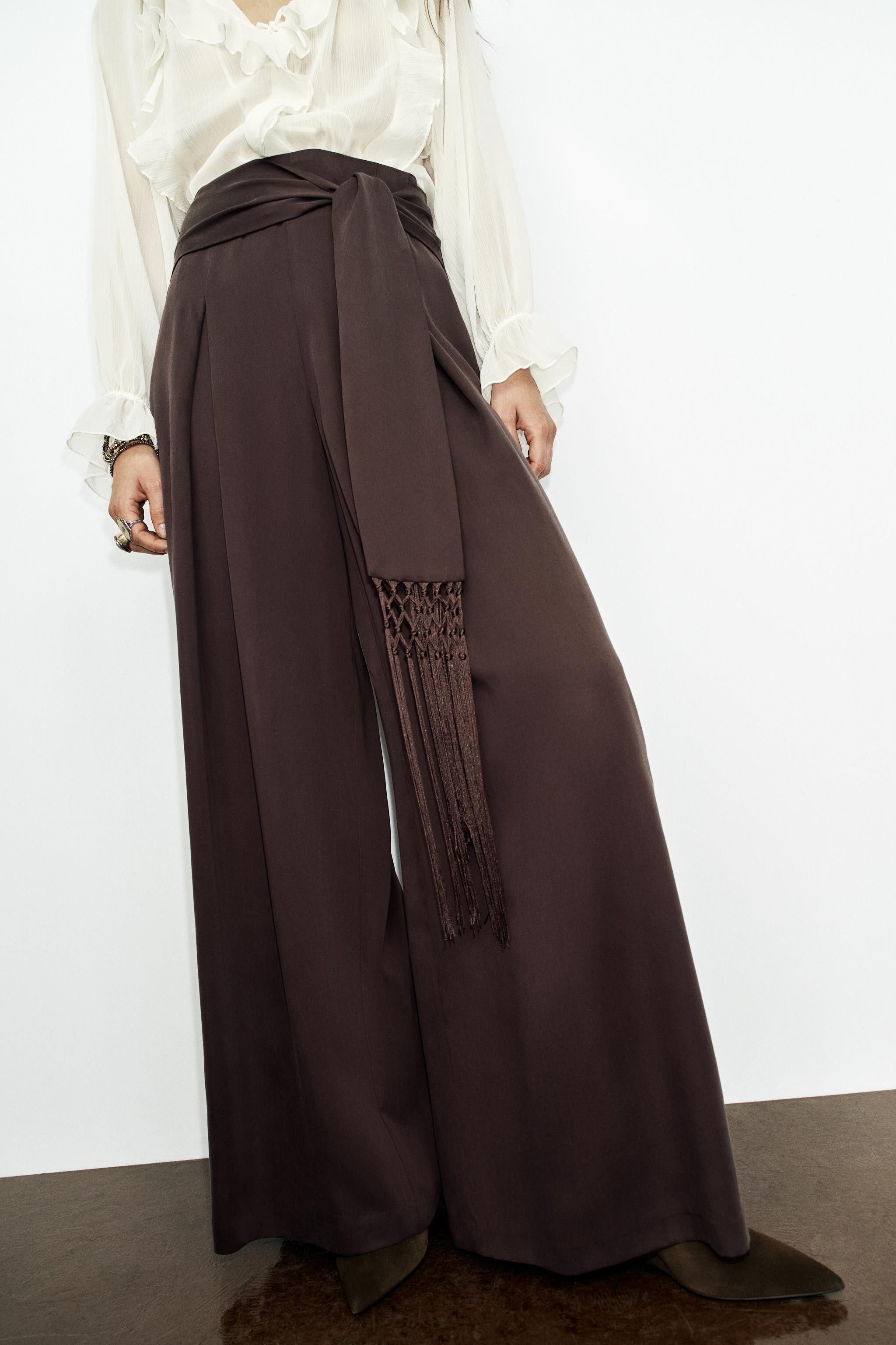 High-waisted trousers with fringe belt detail. Front pleats and wide-leg design. Concealed back z... | Zara US