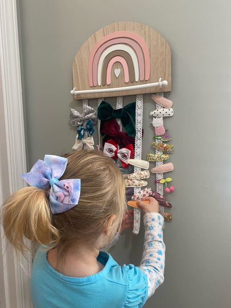 Coco loves her rainbow bow holder! We hung low enough so she can  get and out back her bows and clips. Love that has the bar that you can put bands around also. Little girl bedroom, toddler girl hair bow holder 

#LTKbaby #LTKhome #LTKkids