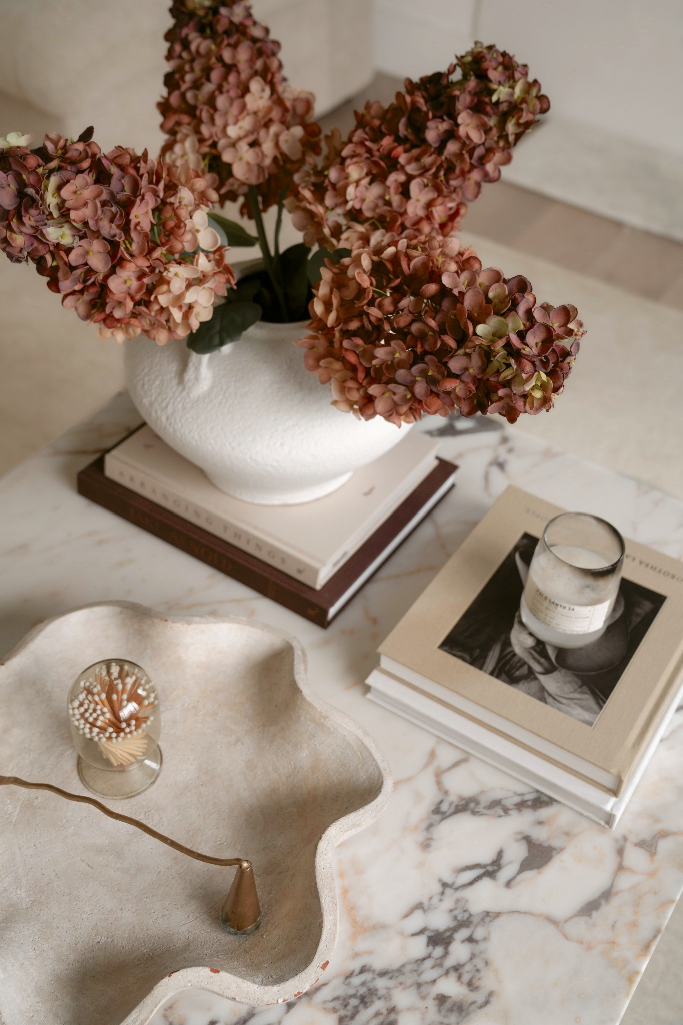 Coffee table styling basics: a layered stack of books, textured florals, and a sculptural tray for function + form. I always anchor with something organic—like these faux cone hydrangeas—and build around neutral tones for a soft, collected feel. Everything’s linked here 🤎 

[ this exact wavy bowl is from home goods so no link but I found sumilar ]

#coffeetablestyling #neutralhome #LTKhome #fauxflorals #collectedhome

#LTKFindsUnder50 #LTKSeasonal #LTKHome