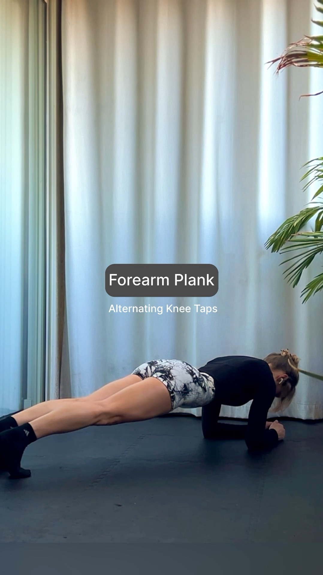 Forearm planks with alternating knee taps in a long sleeve black top, black and white marble scrunch butt gym shorts, and black crew socks. 

#LTKFitness #LTKVideo #LTKActive