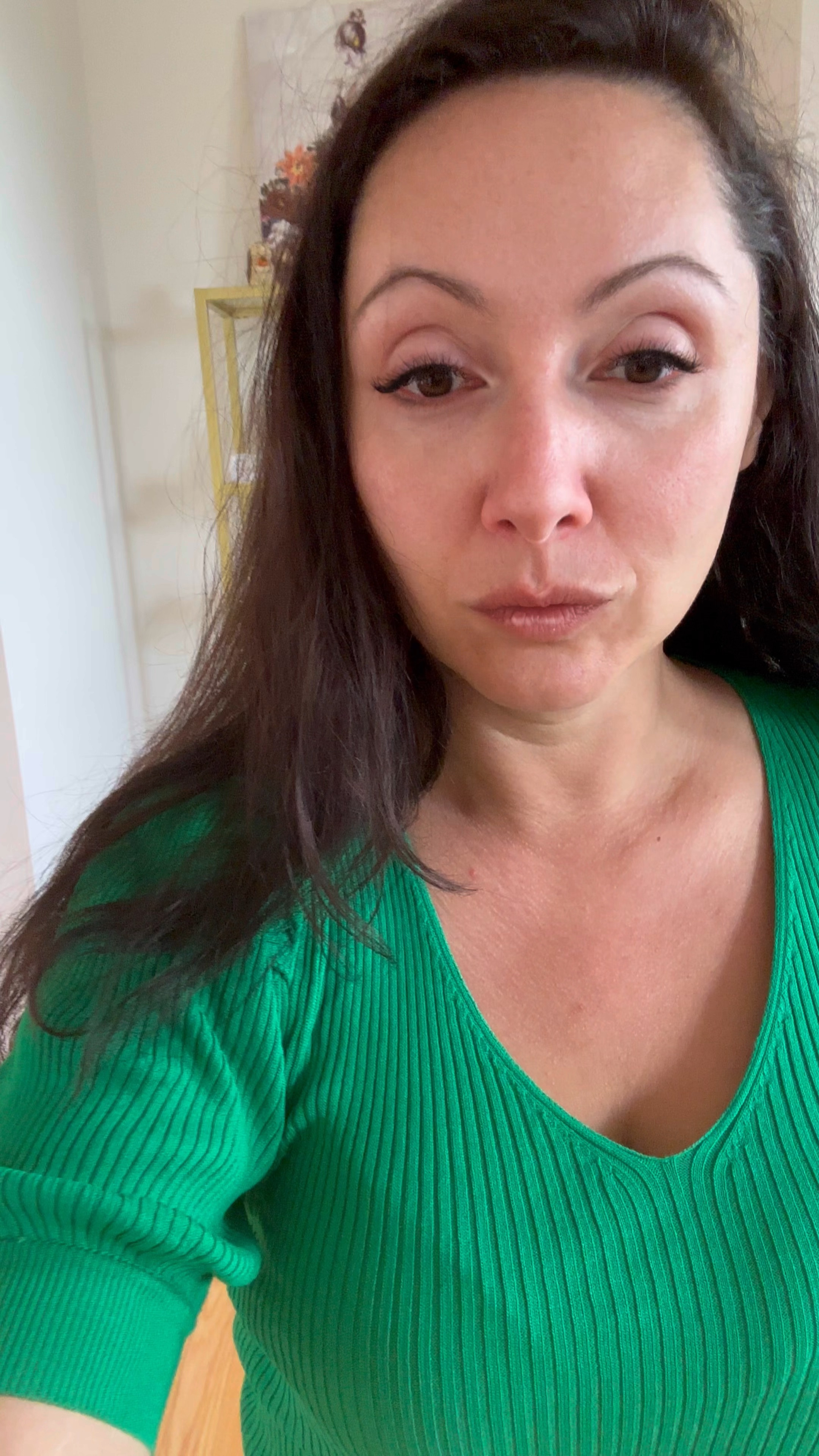 The image features a woman standing indoors in front of a tall, gold-colored shelving unit. She has long, dark hair and is wearing a green ribbed top with short sleeves and a brown leather skirt. Her shoes are brown ankle boots. She is posing with one hand on her hip and the other hanging by her side.

The shelving unit behind her is decorated with various autumn-themed items:
- On the top shelf, there is a floral arrangement and a small figurine.
- The second shelf from the top has a small pumpkin and a decorative item next to it.
- The third shelf holds more pumpkins and a lantern.
- The bottom shelf contains additional pumpkins and some decorative items.

To the right of the shelving unit, there is a black bag on the floor, and to the left, there is a blank wall. The floor is wooden and the overall setting suggests a cozy, autumnal atmosphere.

#LTKSaleAlert #LTKMidsize #LTKFindsUnder50