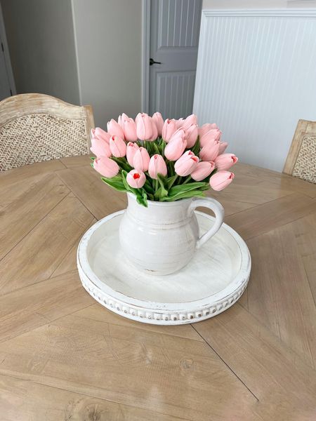 My gorgeous dining table looks even prettier with this simple home decor combination. This white round wood tray with farmhouse pitcher vase and pink tulips is just perfect! #amazon #amazonhome #founditonamazon #homedecor #diningtable #diningroom #tablecenterpiece #farmhousedecor #coastaldecor #tray #trays #fauxtulips #mandytulips #pitcher #woodtray #home

#LTKhome