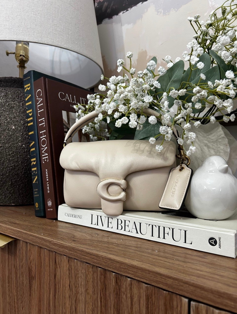 Soft neutrals, cozy textures, and a little touch of luxe 🤍✨
Styling moments like this just makes home feel extra calm and elevated. The mix of warm wood, stacked coffee table books, and fresh florals = effortless beauty.

Bag of the day: my Coach Pillow Tabby 18 in the dreamiest neutral… she fits right in 🤍

This is your reminder that the little corners matter 🌿

#homedecor #cozystyling #neutralhome #interiorinspo #shelfstyling #coachbag #luxeliving

#LTKMothersDay #LTKOver40 #LTKSeasonal