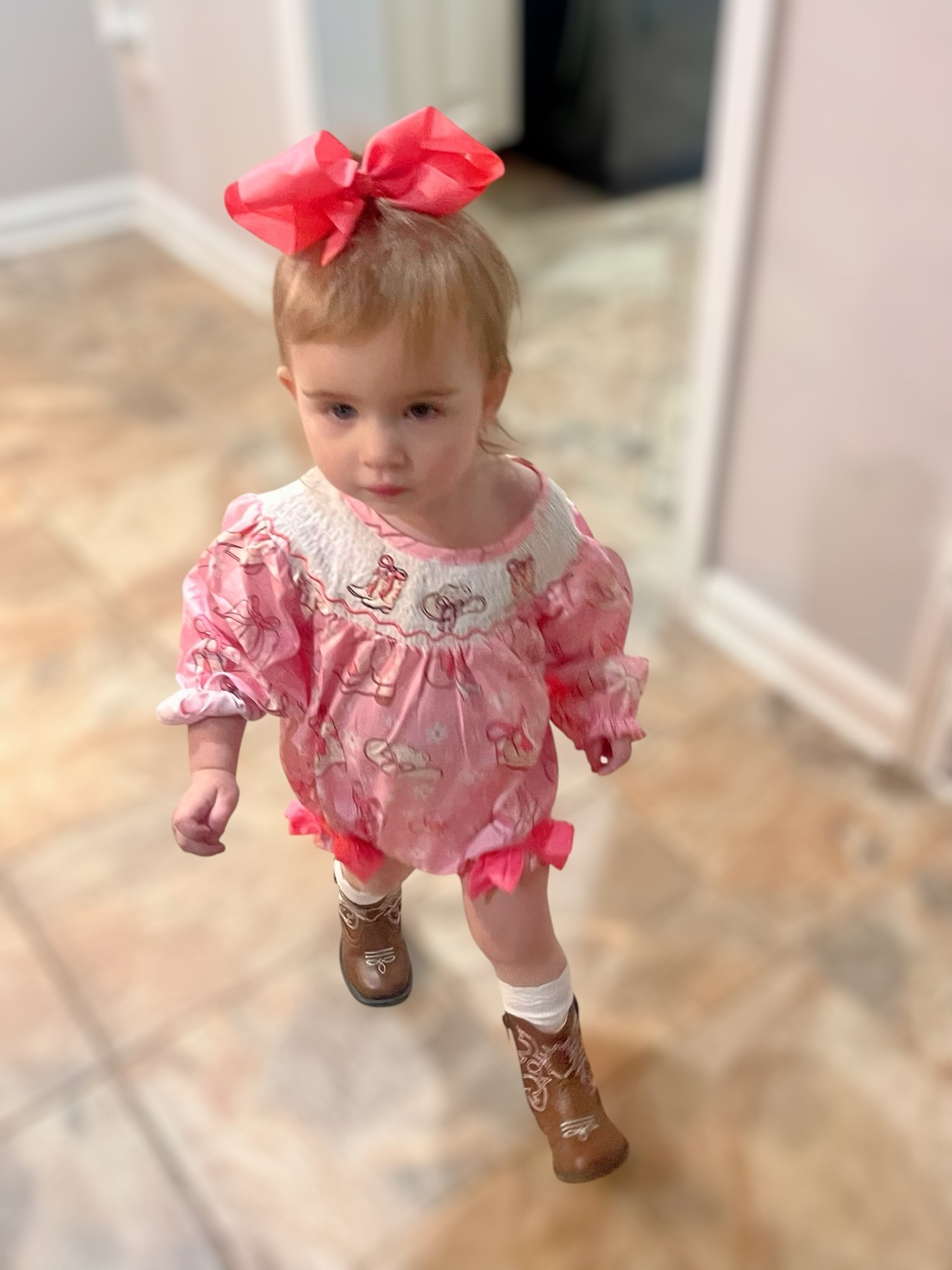 Caroline’s little cowgirl moment 🤎👢 This pink smocked romper with bow details is such a girly yet classic baby outfit. I paired it with white knee-high socks, the cutest toddler western boots from Walmart, and a big pink hair bow 🎀 for a picture-perfect toddler style. This look is adorable for fall photos, pumpkin patch outings, or just everyday toddler girl fashion. Affordable finds from Amazon & Walmart that give major boutique vibes at budget-friendly prices!

📌 Linked everything so you can recreate this toddler western outfit for your little one!

⸻


	•	toddler girl western boots Walmart
	•	baby girl smocked romper Amazon
	•	pink bow toddler girl outfit
	•	baby girl cowboy boots outfit
	•	affordable boutique toddler clothes
	•	girly toddler fall outfit
	•	toddler girl hair bows Amazon
	•	toddler cowgirl outfit ideas


#LTKFindsUnder50 #LTKBaby #LTKKids