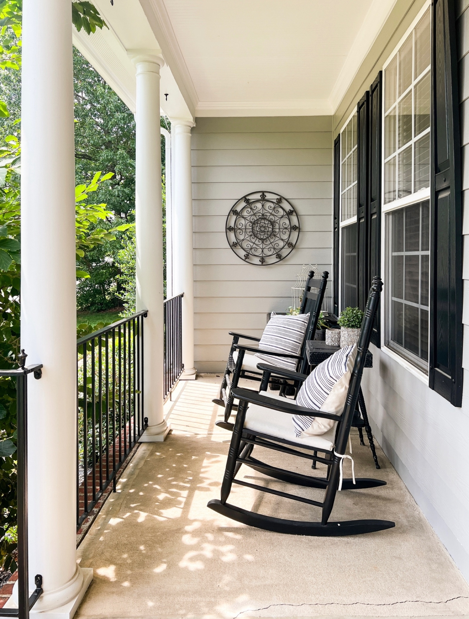 Rocking chair porch. Black rocking chairs. Blue and white striped pillow covers. Cream seat cushions. Iron medallion wall art.

#LTKFind #LTKhome #LTKstyletip