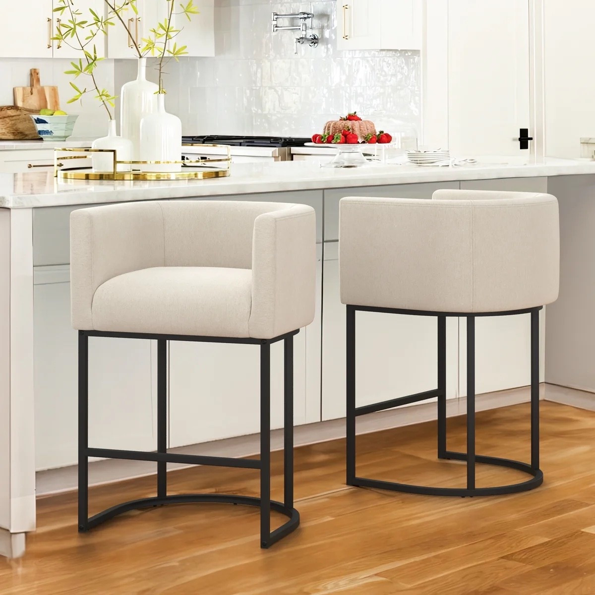 This set of 2 counter-height stools from Wayfair has such a clean, polished look for a kitchen island. I love the 27-inch height, cream linen-look upholstery, barrel-style backs, built-in arms, and slim black metal frames. They feel cozy enough for lingering over coffee but still streamlined for a bright kitchen setup.