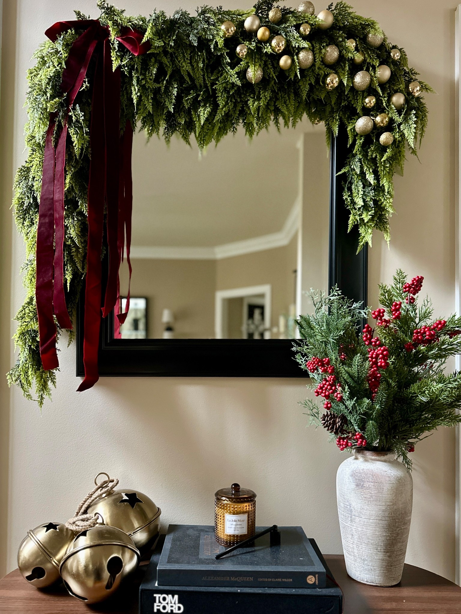 Christmas styled entryway table with rustic jingle bells, Christmas greenery with berries, and a soft cedar garland with garland ornaments and burgundy velvet ribbon  

#LTKHome #LTKHoliday #LTKFindsUnder100