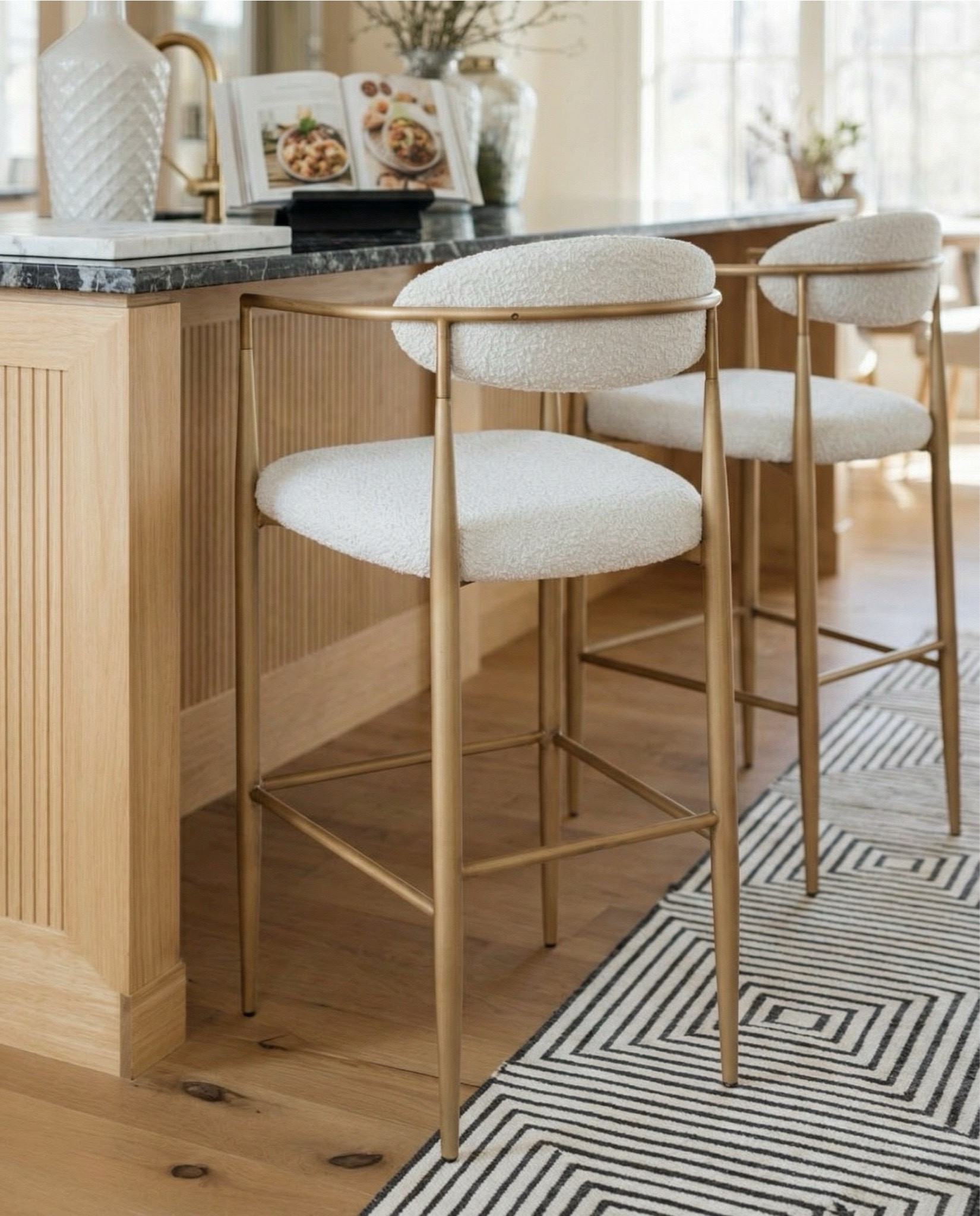 Check out our kitchen design with these gorgeous light oak bar stools with white textured fabric. This black checkered runner rug was perfect to pair with the black element in this kitchen. To add alittle elegance, we added white glossy globe pendant lights to brighten up the space. The white textured vase, and white marble cutting board also help lighten up the space. A perfect space for cooking with a recipe holder.  

#LTKHome #LTKSaleAlert