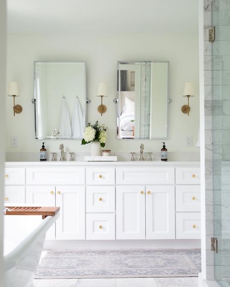 White bathroom design, mixed metal, pivot mirror, brass sconce, white double vanity, marble, soaking tub, bathroom runner 

#LTKFind #LTKstyletip #LTKhome
