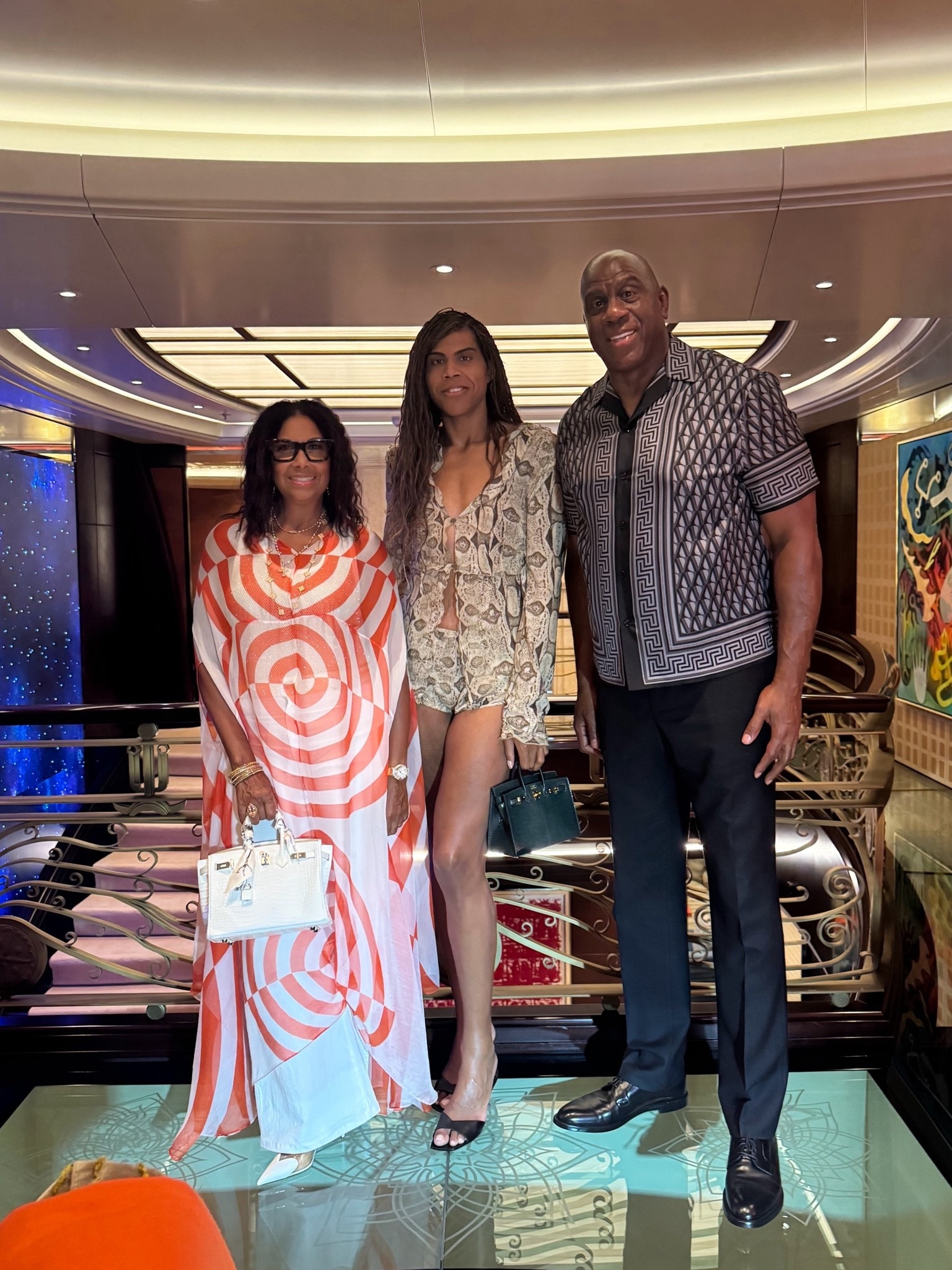 @magicjohnson , @thecookiej , and @ejjohnson_ enjoyed dinner in Croatia, with #cookiejohnson in a @driesvannoten red silk cape gown and a white matte crocodile #hermes Birkin, #ejjohnson in a $2,500 @gucci snake-print silk-chiffon shirt with $890 matching shorts and a green #hermesbirkinbag, and #magicjohnson in a @versace Printed Silk Twill Slim Shirt. Hot! Or Hmm..?
Find a link to purchase EJ’s look in our bio! 
📸
magicjohnson ‘s IG  ejjohnson cookiejohnson fashionbombdaily