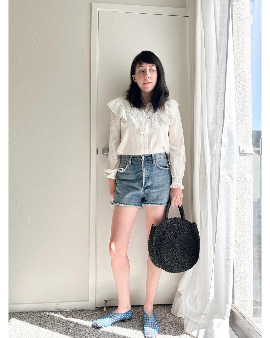 Sézane ruffle top is perfect for denim shorts. These Agolde denim shorts are my favorite plus Clare V woven purse and the row jelly dupes from Amazon (they’re really comfy)