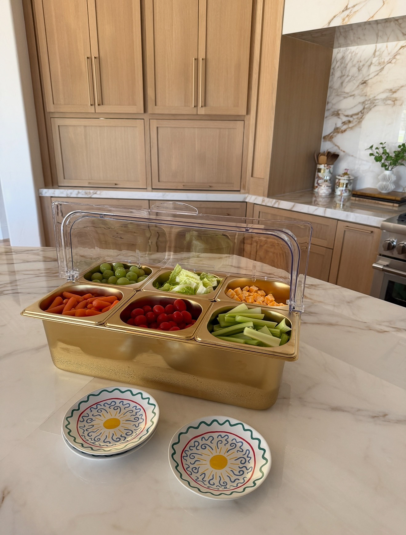 This six-compartment snacking station in gold with a clear lid feels equal parts serving tray and display piece. Something designed not just for convenience, but for presentation. The overall effect is organized, elegant, and inviting. It turns casual snacking into something a bit more intentional. Almost ceremonial, where choosing what to eat becomes part of the experience, guided by neatly separated options and a presentation that feels just a touch luxurious. 

 #LTKfoodie